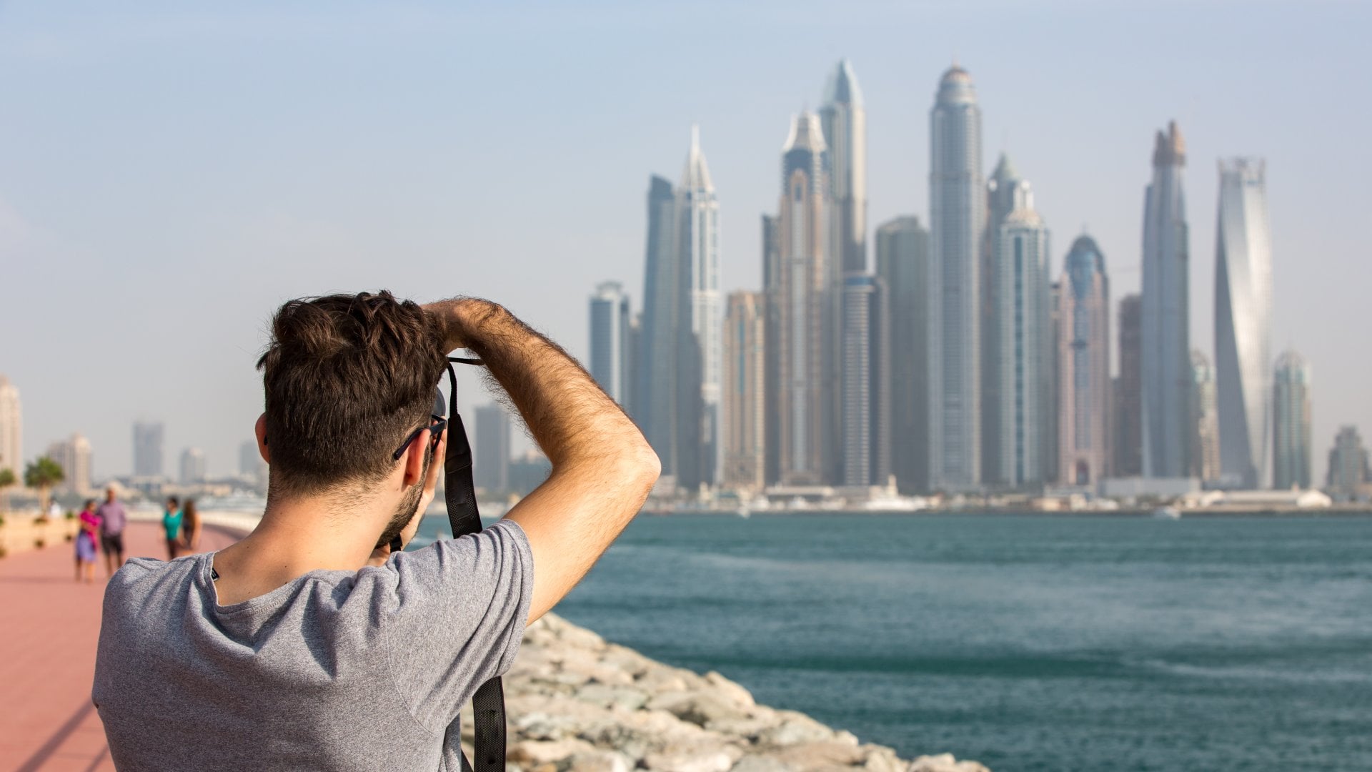 Dubai Marina, Dubai, United Arab Emirates Male Tourist taking photo of the Dubai Marina skyline, United Arab Emirates (UAE)