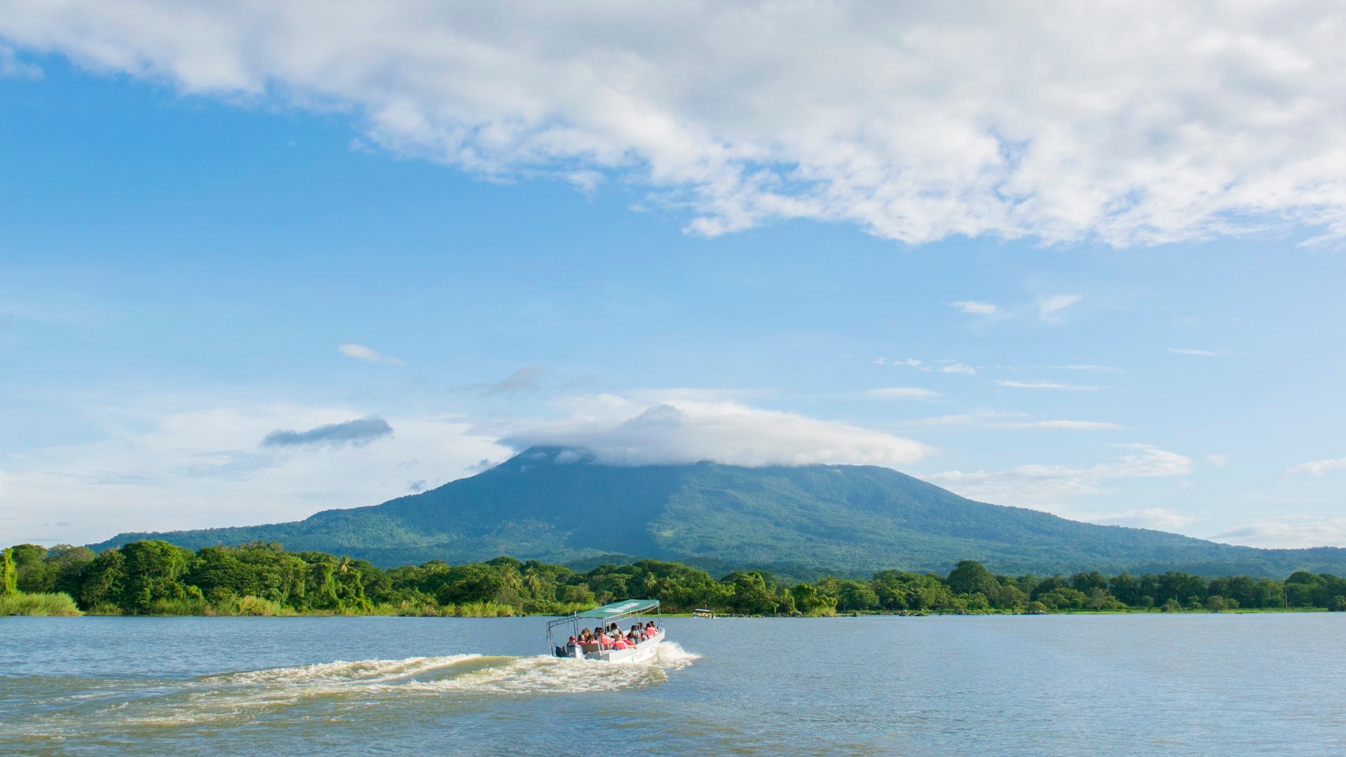 A boat races across a lake in front of Volcan Mombacho in Nicaragua.