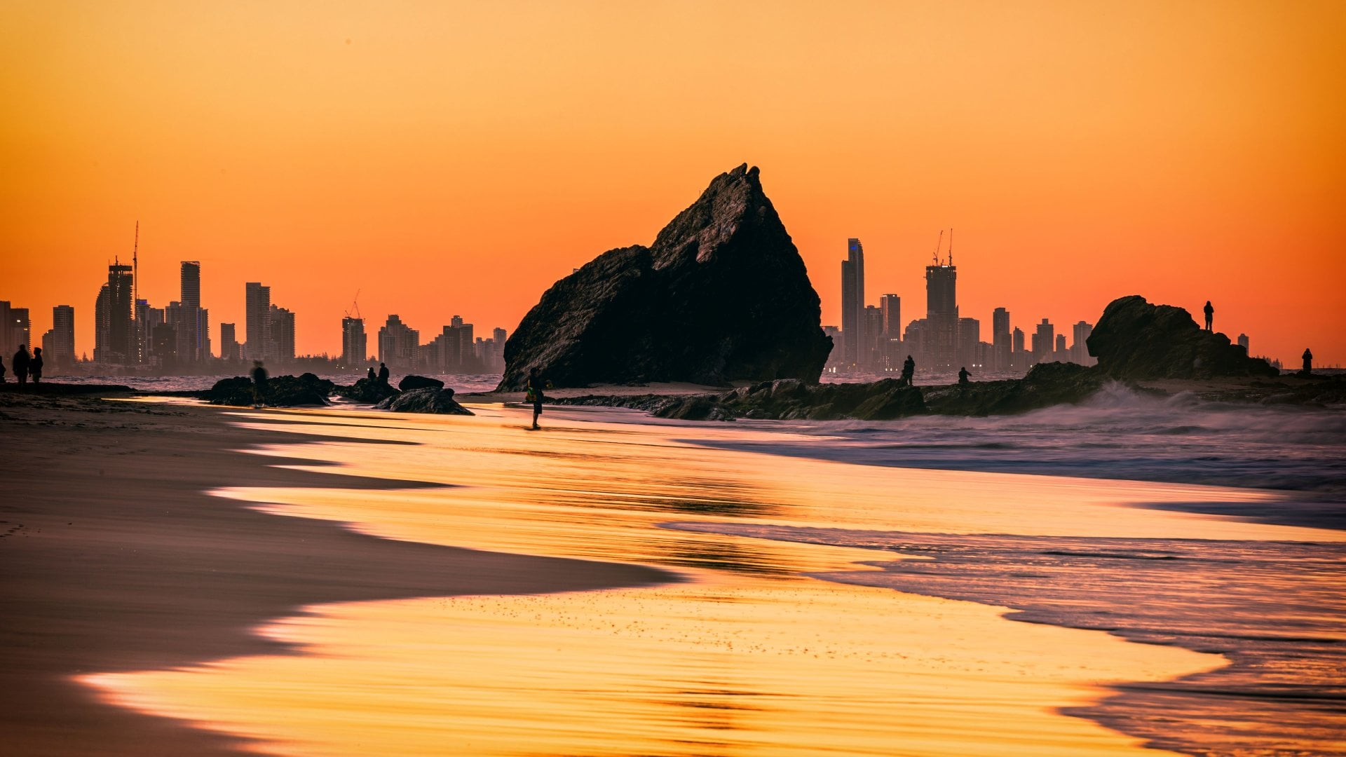 The sunset view of the Currumbin Beach in the twilight and the urban skyline of Gold Coast in the distance