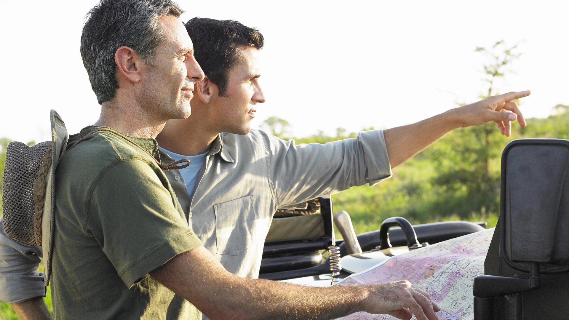 Two male friends with map on bonnet of jeep, Africa