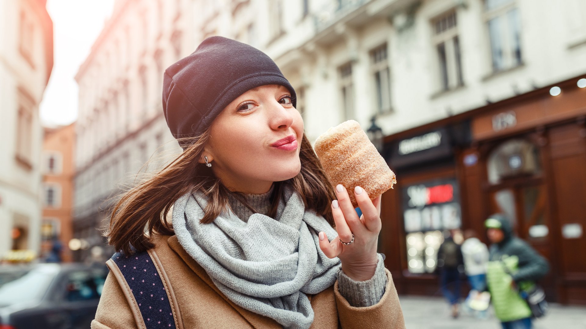 Woman eats trdelnik at a street market in Prague, Czech Republic