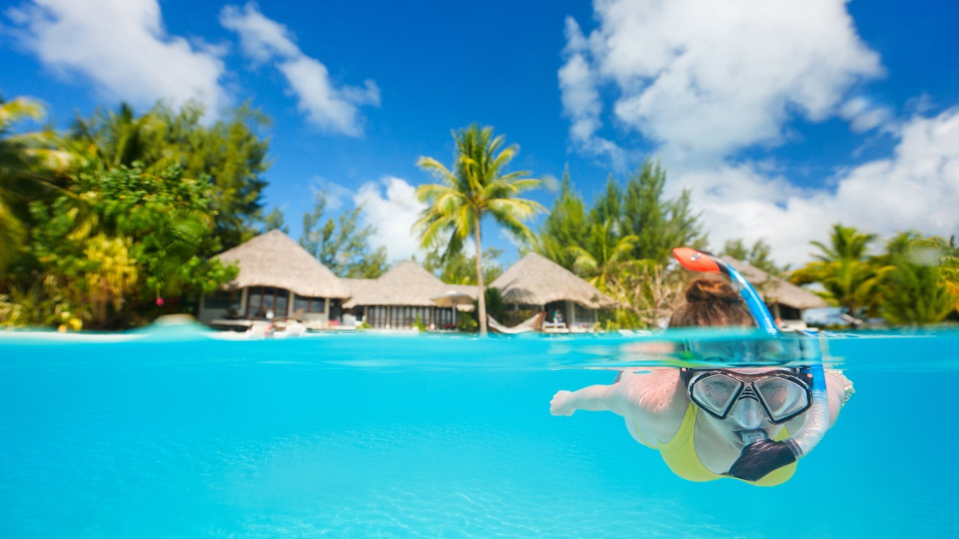 Woman snorkeling in clear tropical waters in front of exotic island, Bora Bora, Tahiti (French Polynesia)
