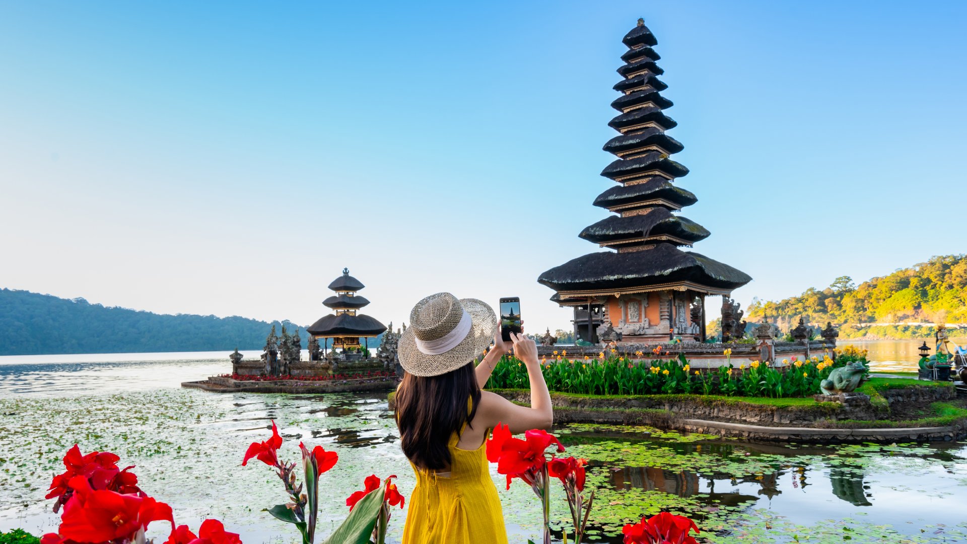 Young woman tourist relaxing and enjoying the beautiful view at Ulun Danu Beratan temple in Bali, Indonesia