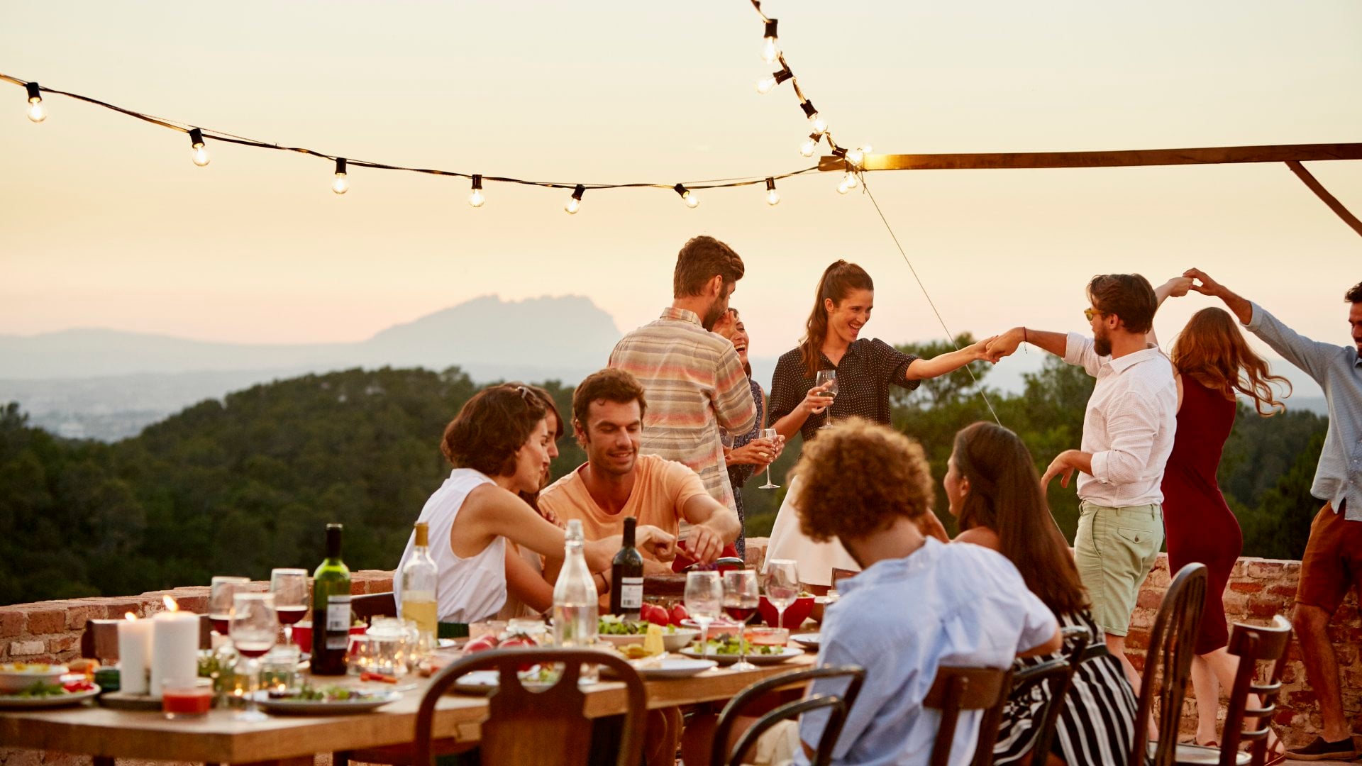 a group of travellers enjoying a meal and dancing while on a terrace in Spain