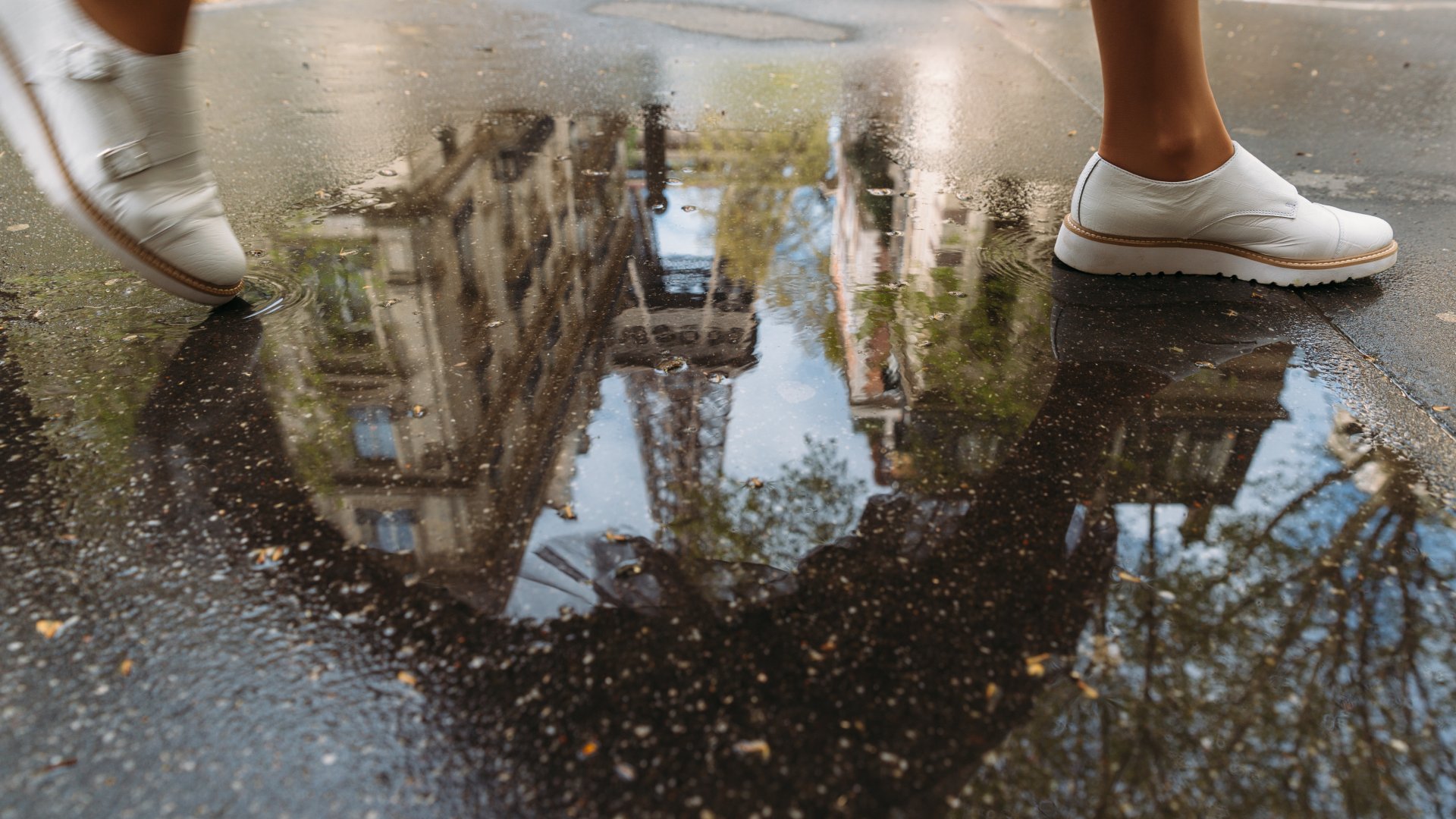 a woman walks through a puddle reflecting the Eiffel Tower on a trip to Paris, France