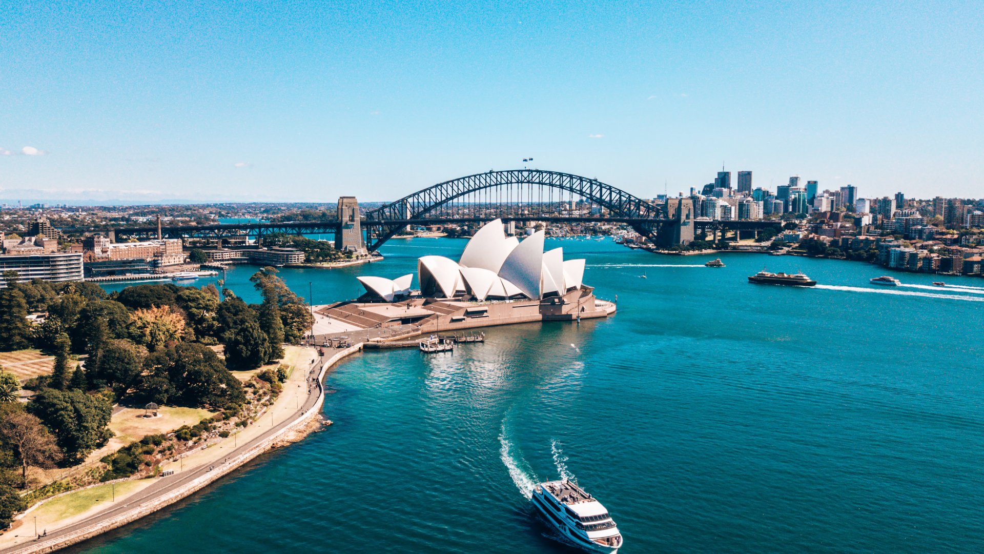 aerial view of harbour and opera house with boat crossing the water
