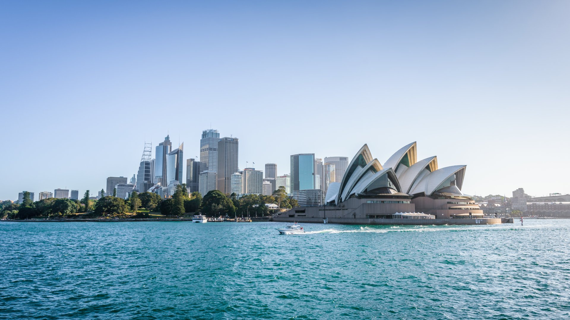 view of opera house and buildings in harbour with blue sky