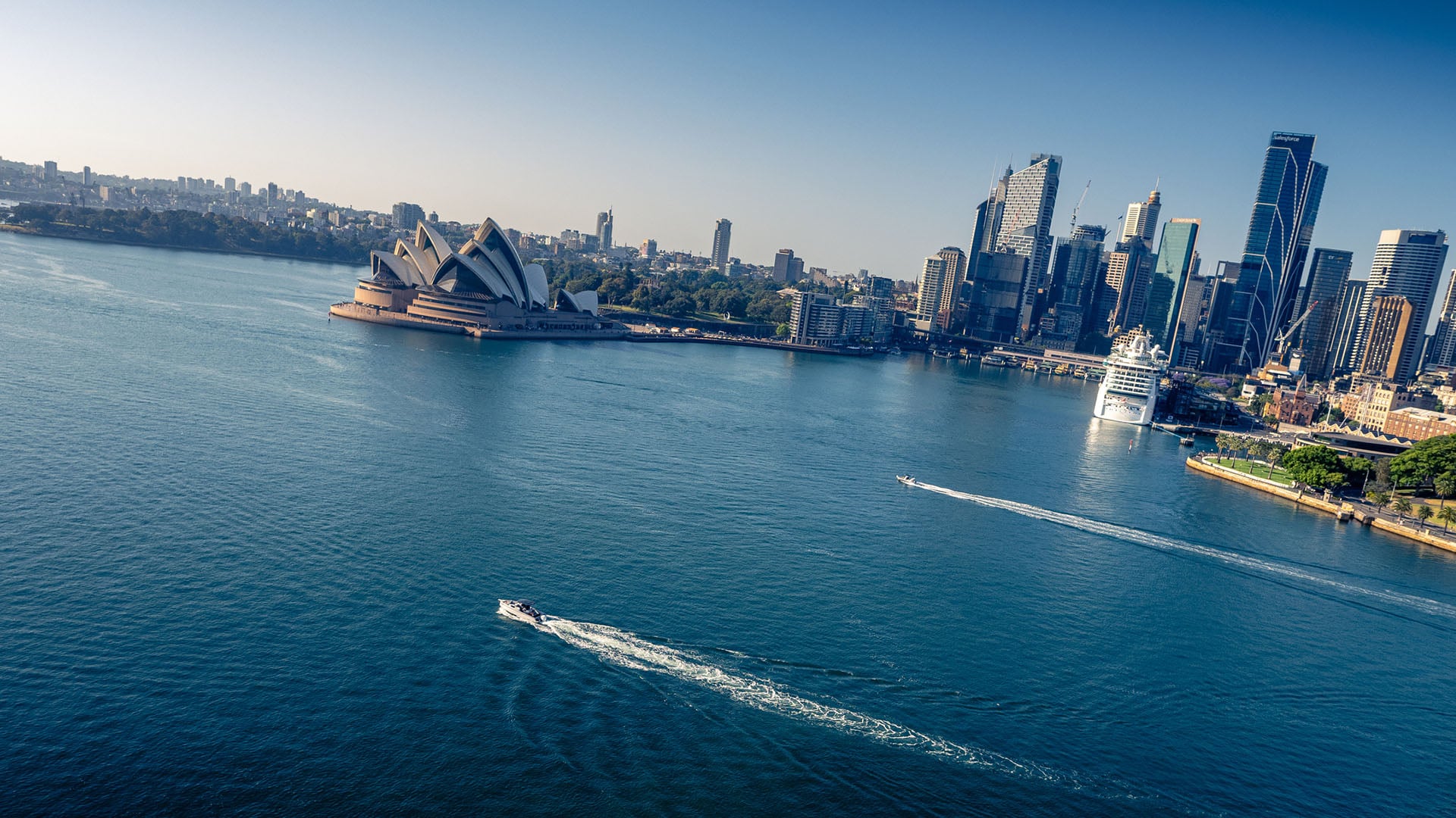 Aerial image of a vessel cruising across Sydney Harbour with the Sydney Opera House in the background.