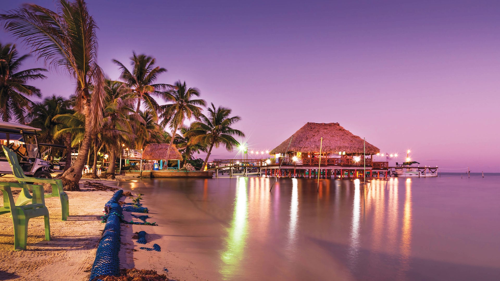 View of the beach at San Pedro in Belize with the sand and palm trees lit up at twilight