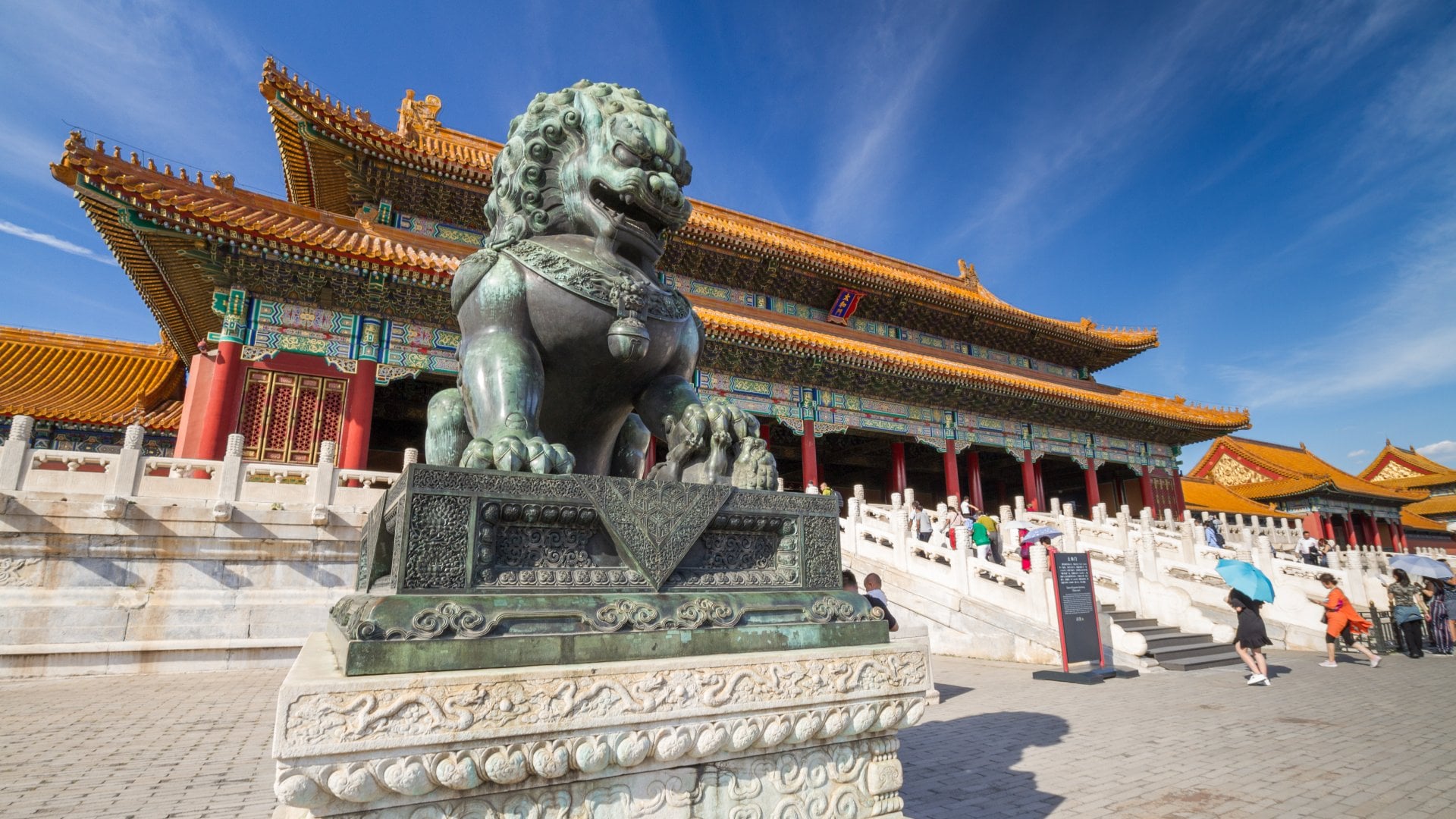 statue of a lion outside a massive chinese palace