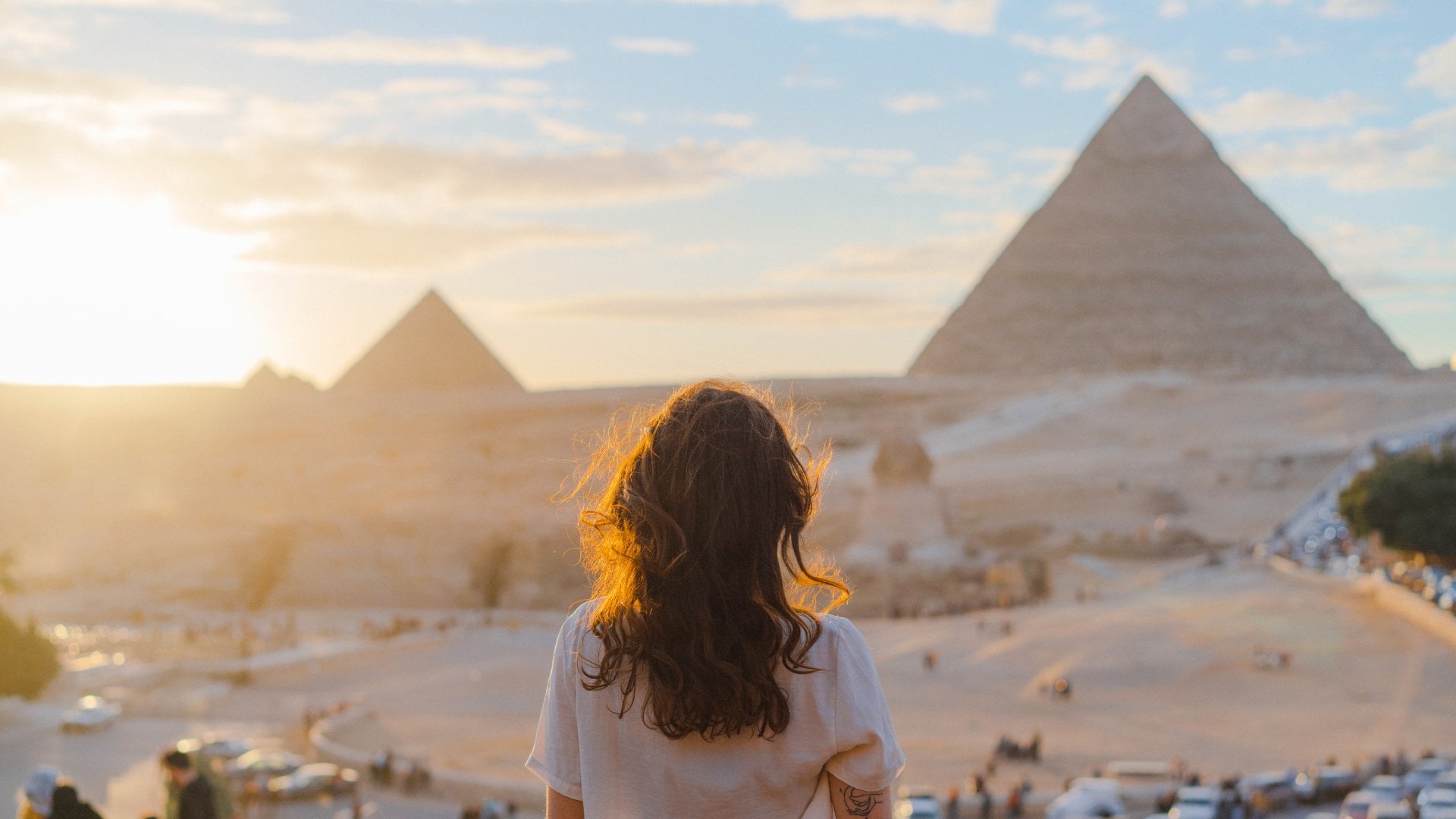 Woman standing on balcony overlooking the pyramids in the distance