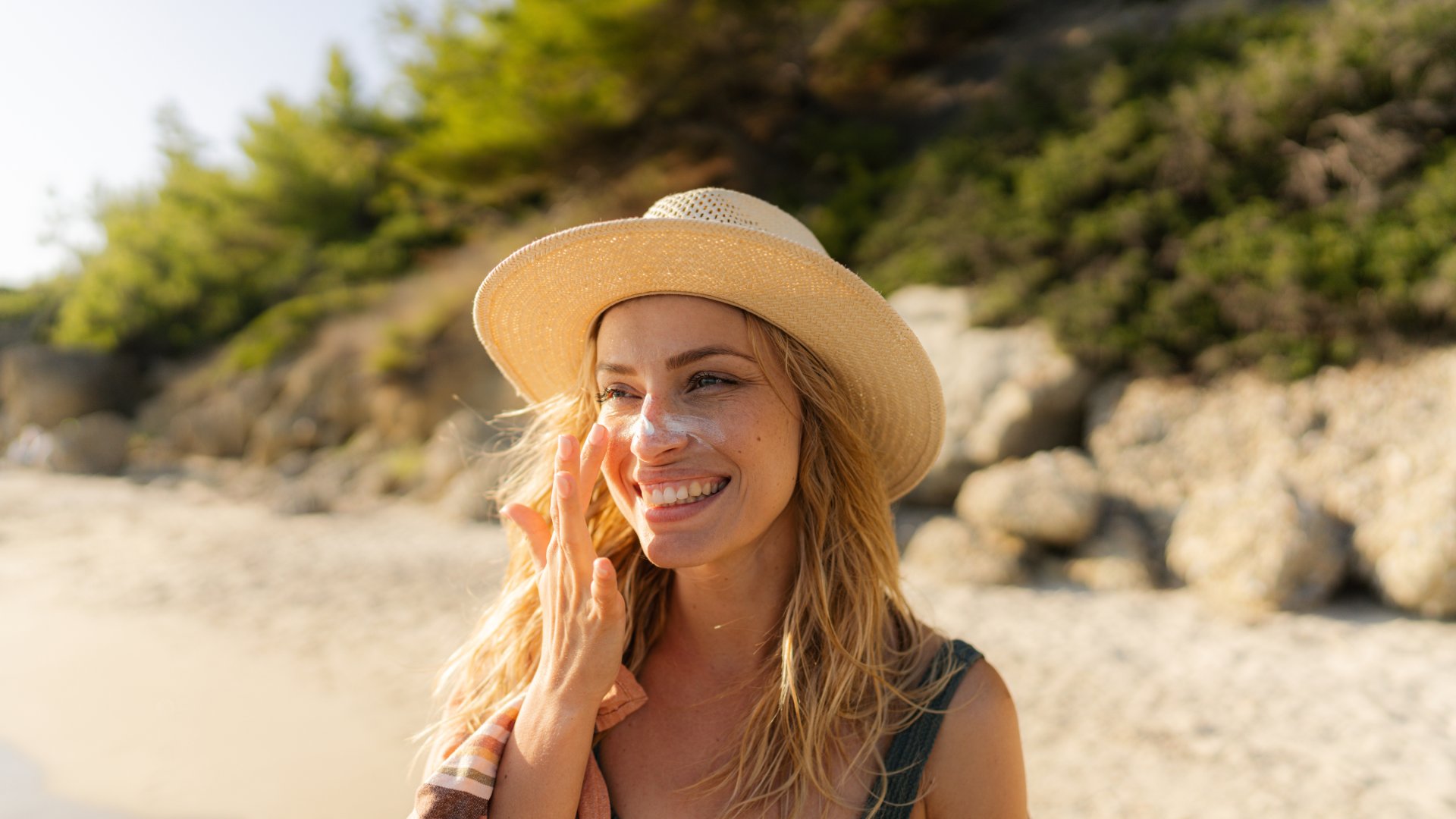 A woman applies sunscreen on a beach in Greece.