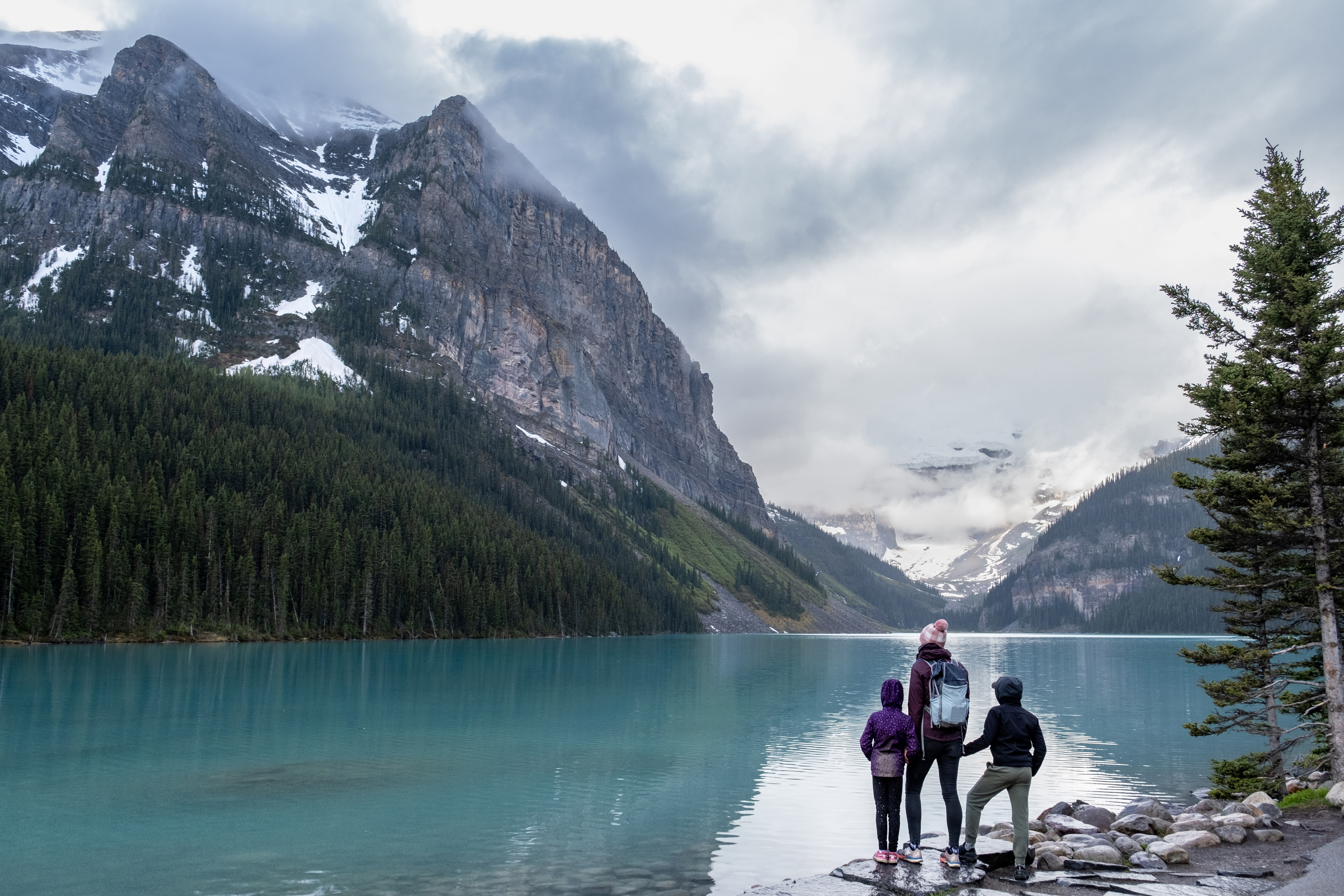 Family hiking around a pristine glacial lake in Banff National Park, Canada.