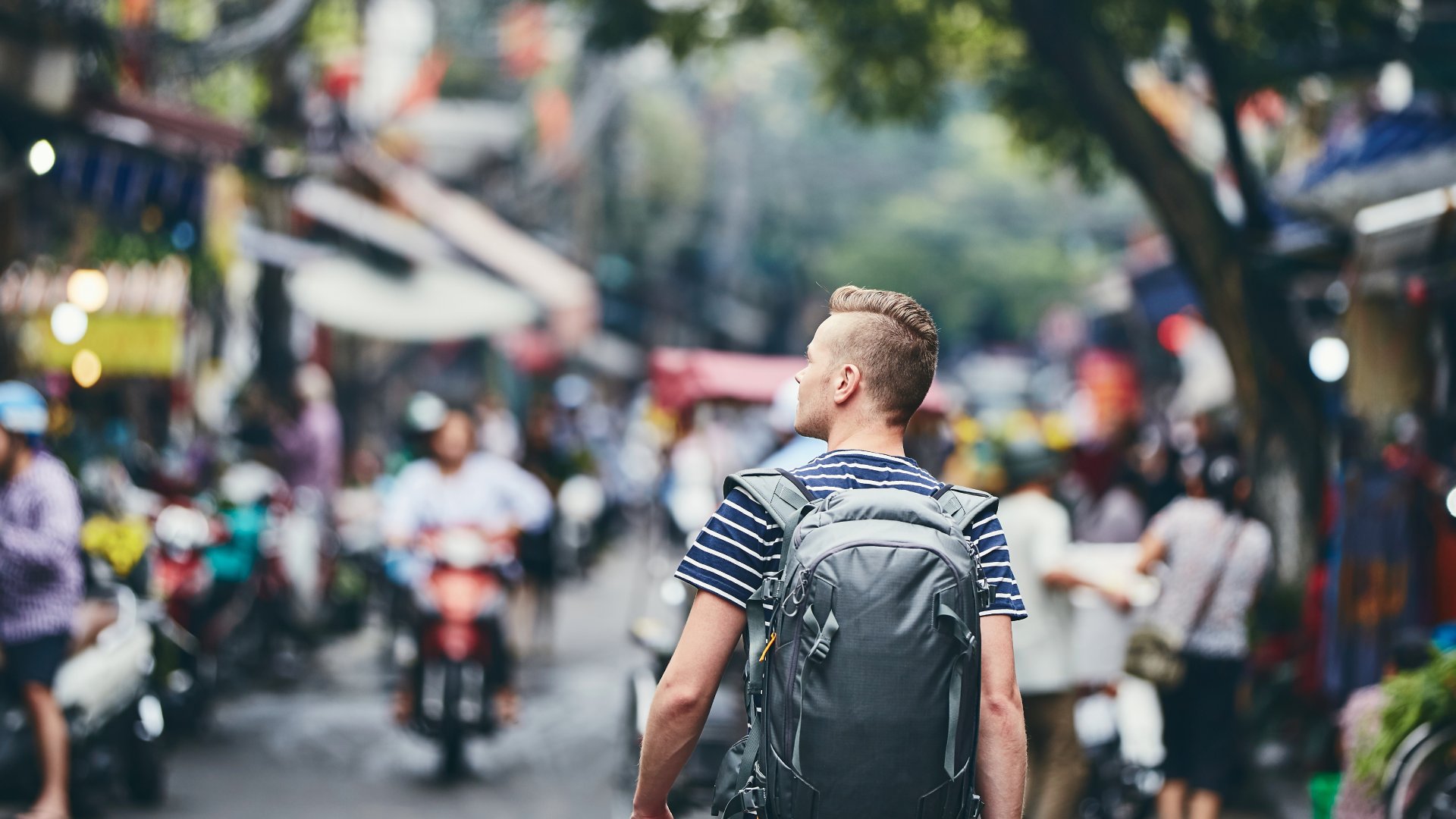 Hanoi, Vietnam man walking down a street with motorbikes and shops