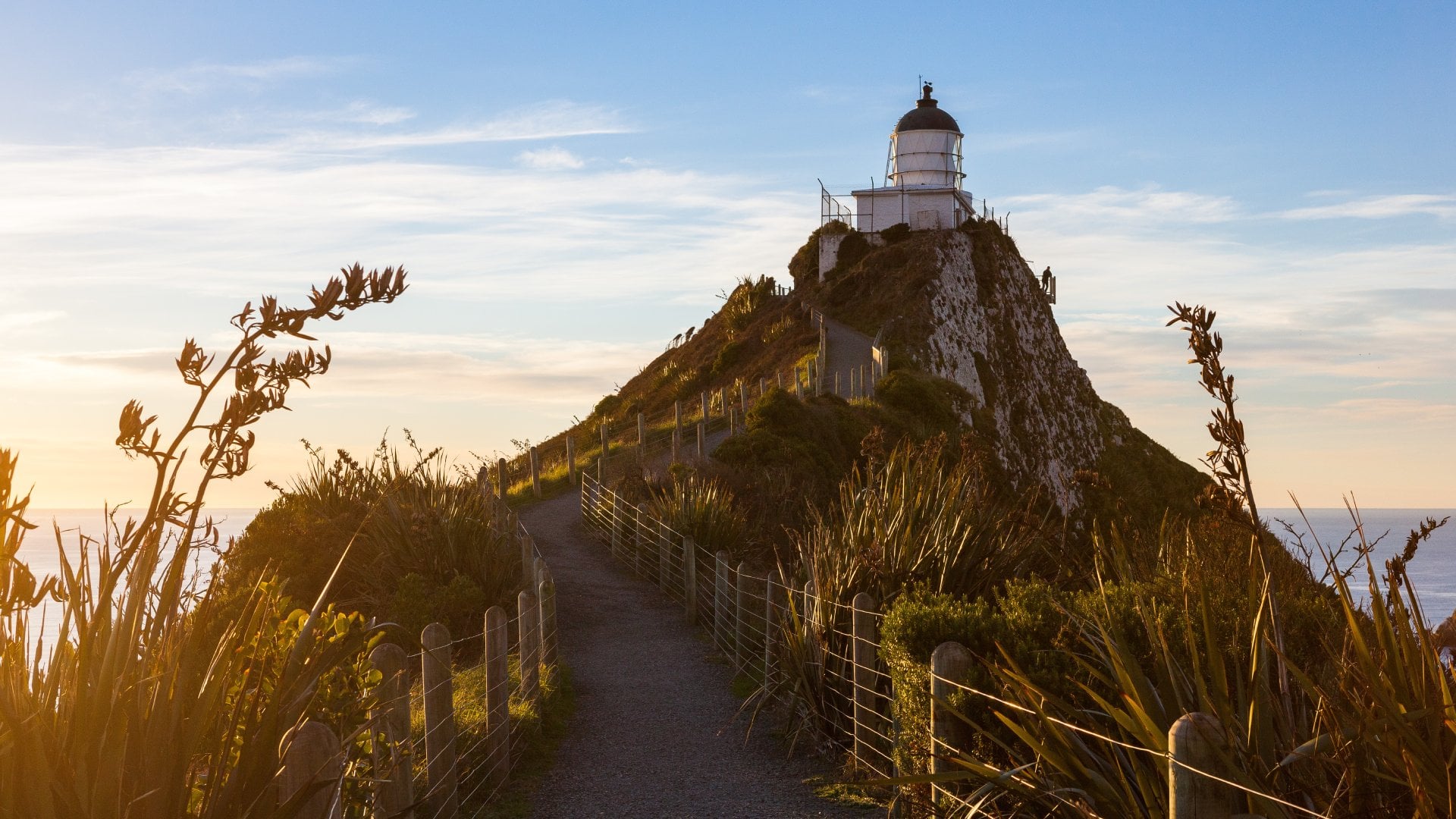 hillside path leading to a lighthouse overlooking the ocean