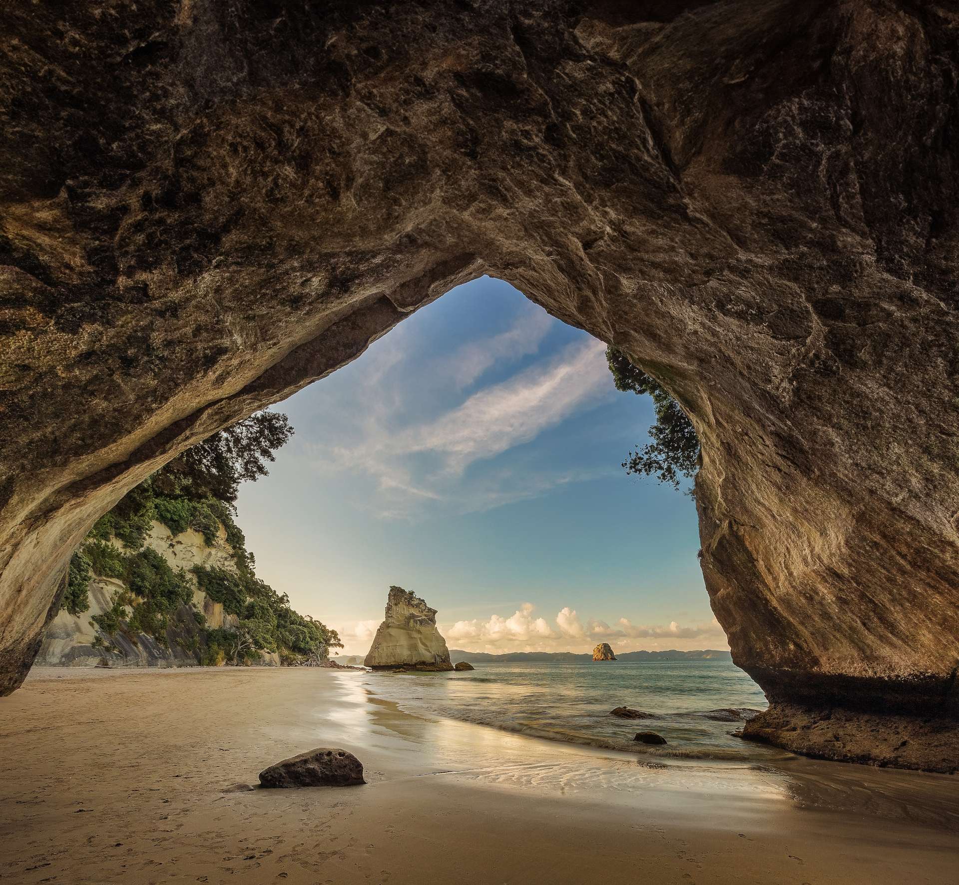 the triangular rock arch of Cathedral Cove gives way to the pristine sands of the bay with forest and ocean beyond