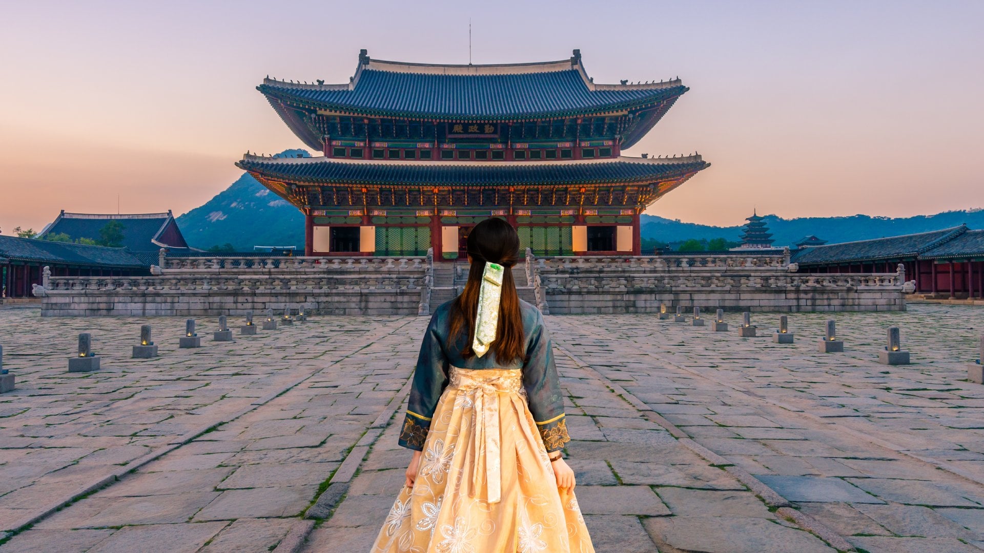 A young woman in a traditional South Korean dress facing Gyeonbok Palace, Seoul.