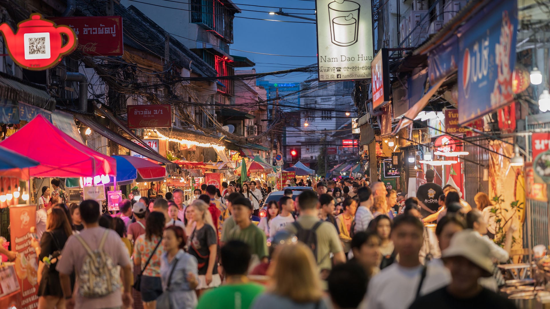 A crowded scene of people eating street food and shopping in Chinatown in Bangkok, Thailand