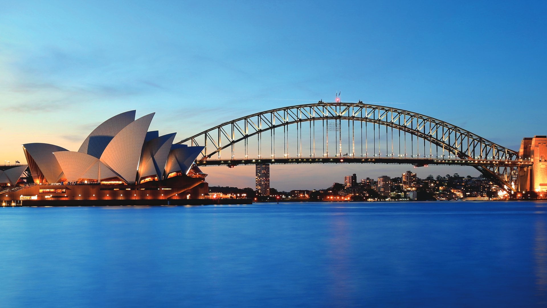 view of harbour bridge and opera house at sunset