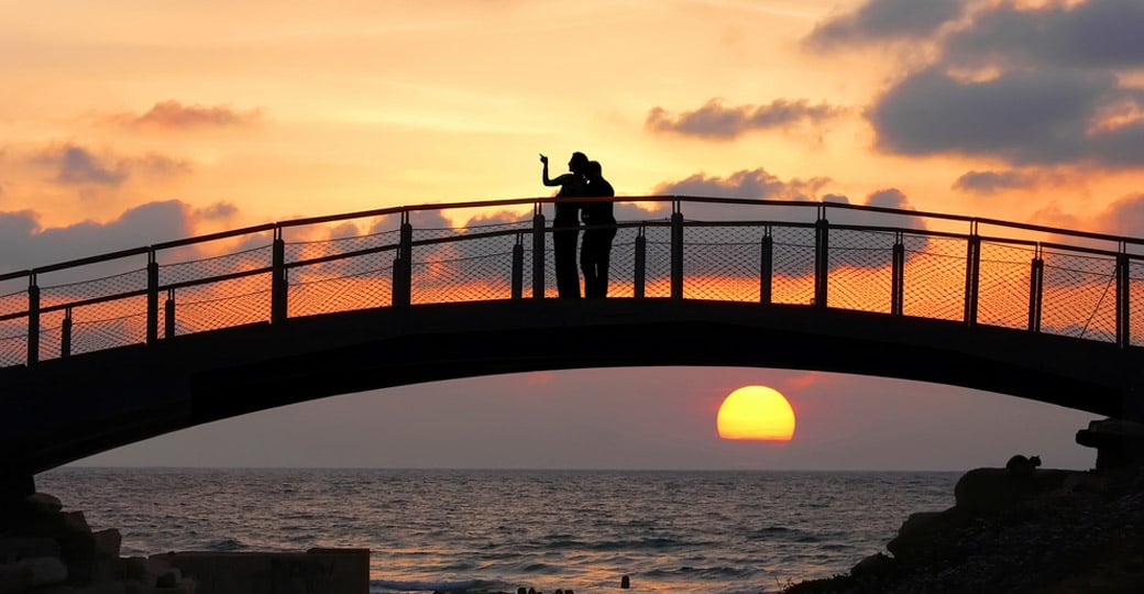 Silhouettes of two people standing on a bridge Silhouettes of two people standing on a bridge