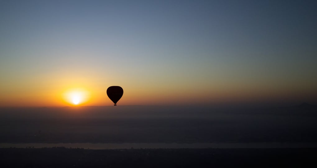 A hot air balloon with the rising sun at dawn over the Nile River A hot air balloon with the rising sun at dawn over the Nile River