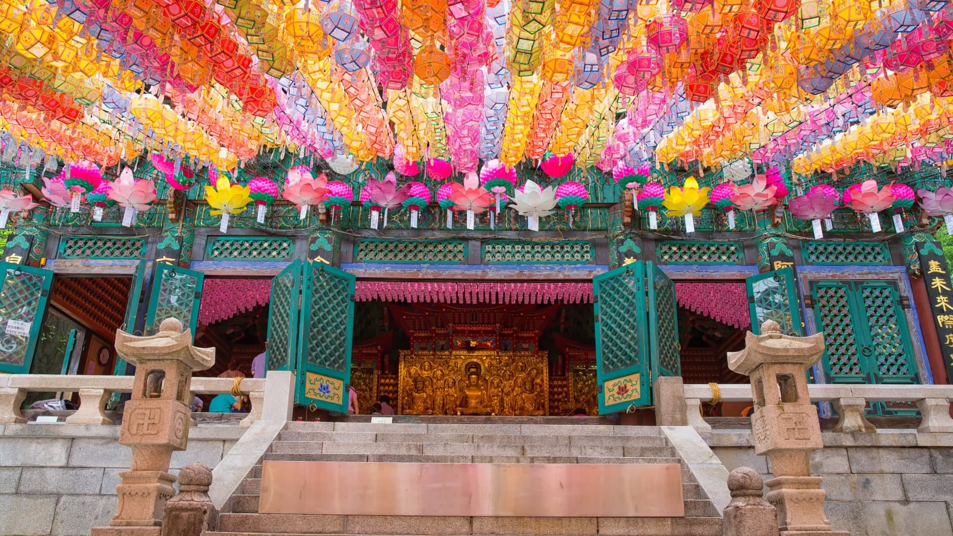 A temple entrance adorned with colorful lanterns hanging from above, creating a vibrant and festive atmosphere.