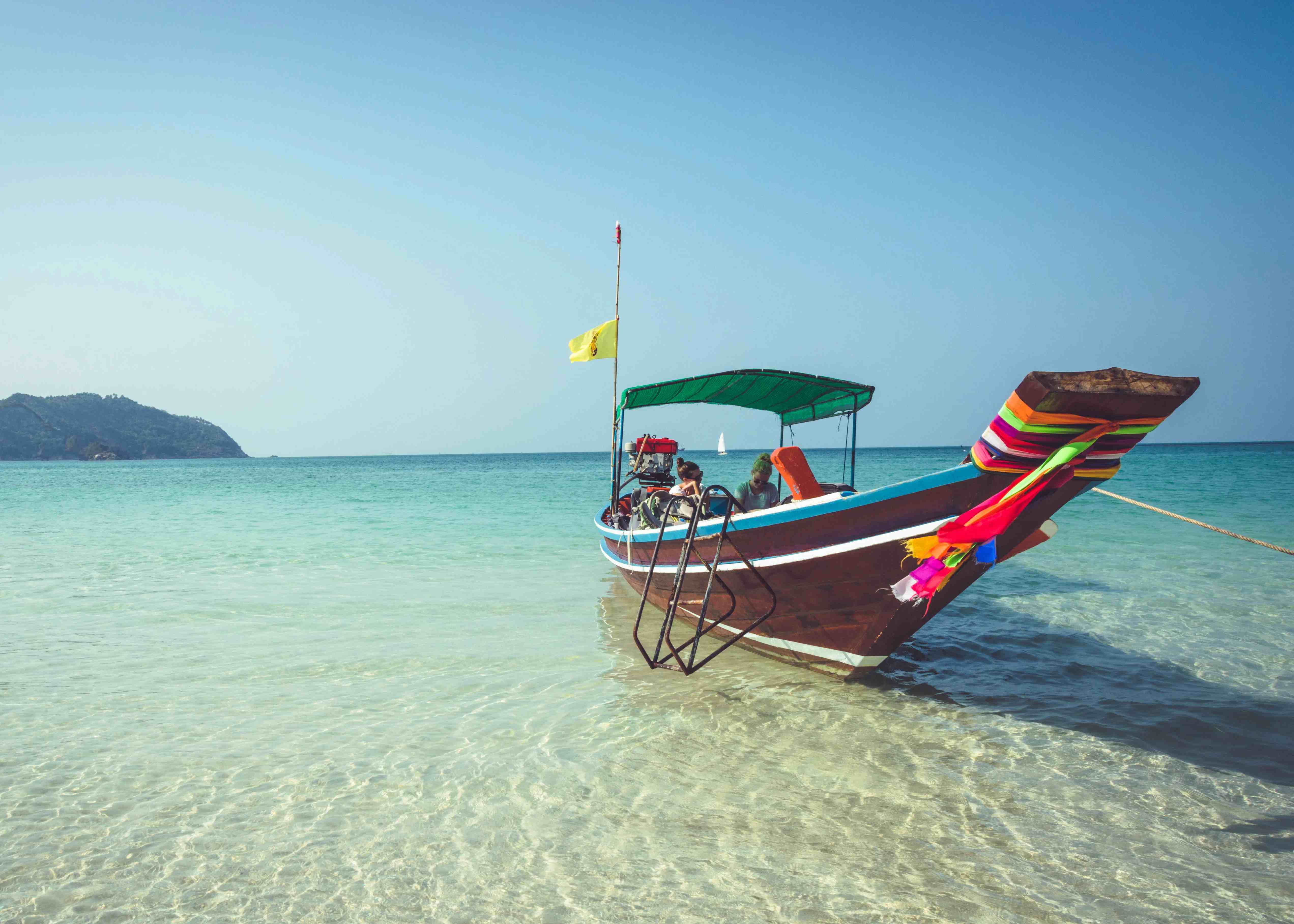 A boat is anchored at the beach, over crystal clear waters