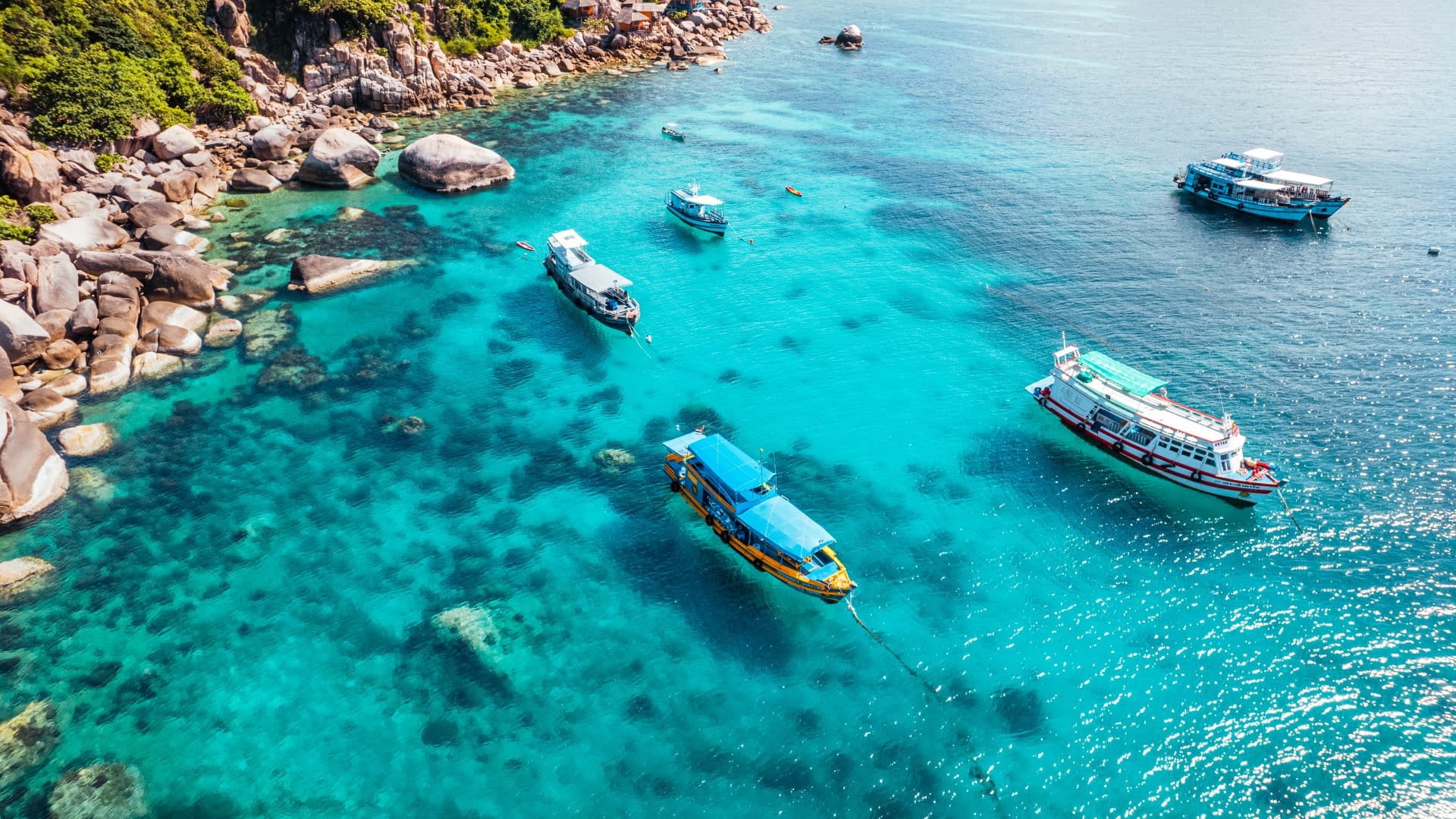 Boats and crystal clear waters at the bay dive site from above
