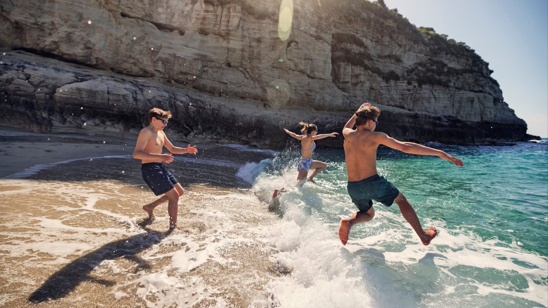 A bunch of happy teenagers running into the surf in Italy