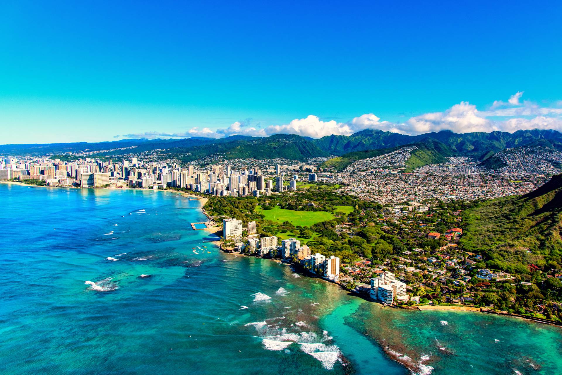 The entire coastline including the base of Diamond Head crater and state park, past the hotel lined Waikiki Beach towards downtown in the distance including the suburban neighborhoods dotting the hills surrounding the city center.