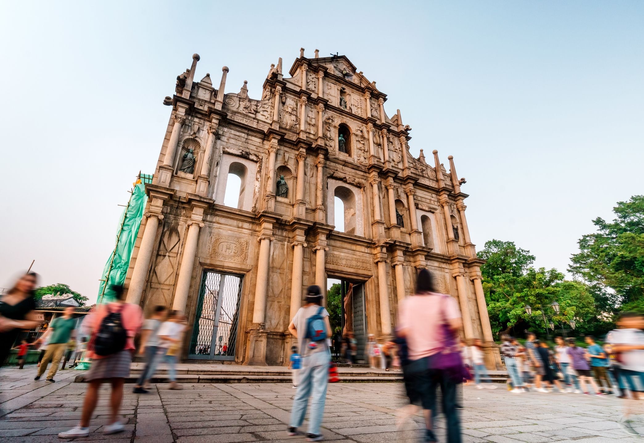 A historic building with ornate architecture, surrounded by people walking in a lively outdoor setting.