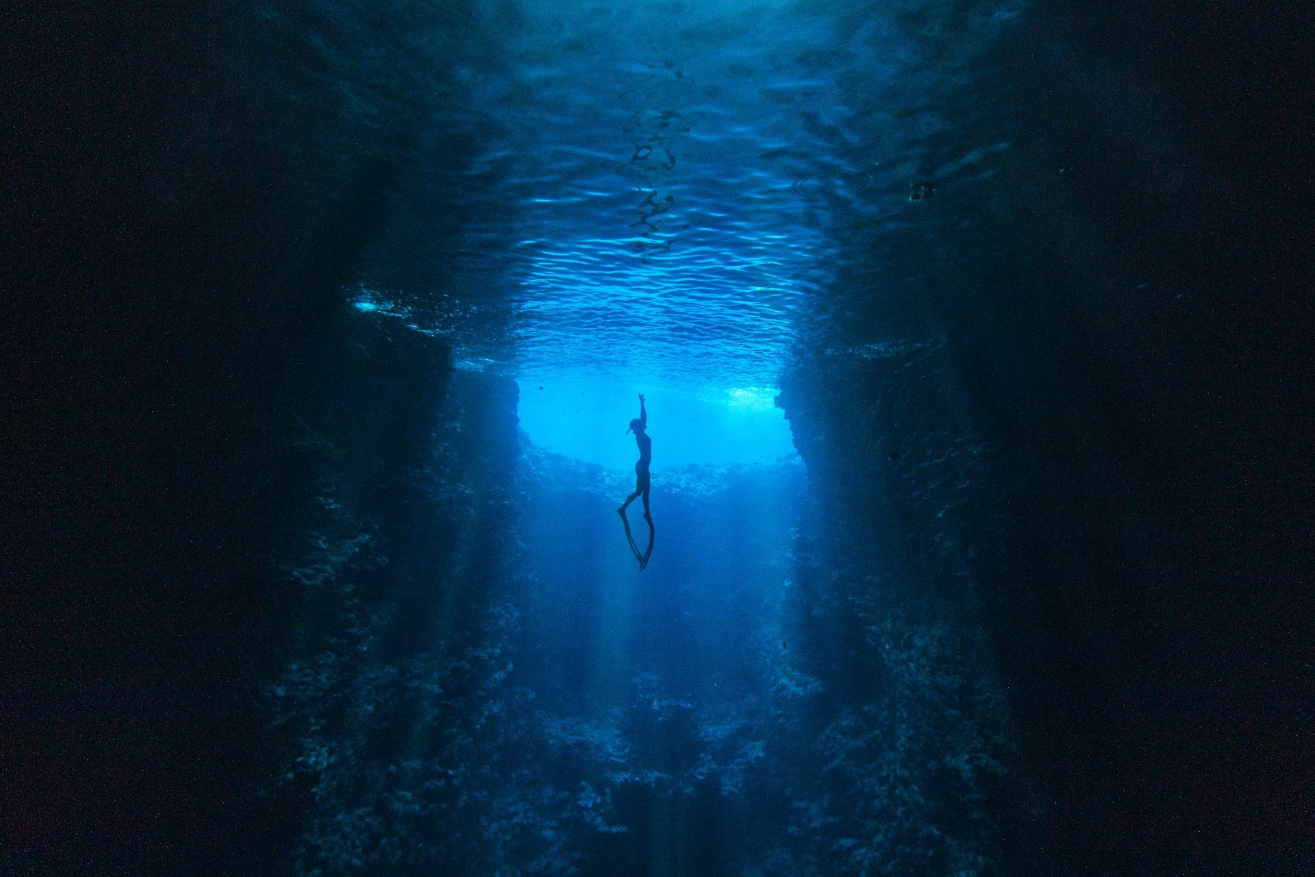 Underwater Cave Diving in Tonga Ocean Diver swimming through the deep blue in an underwater cave towards the sunlight at water’s surface
