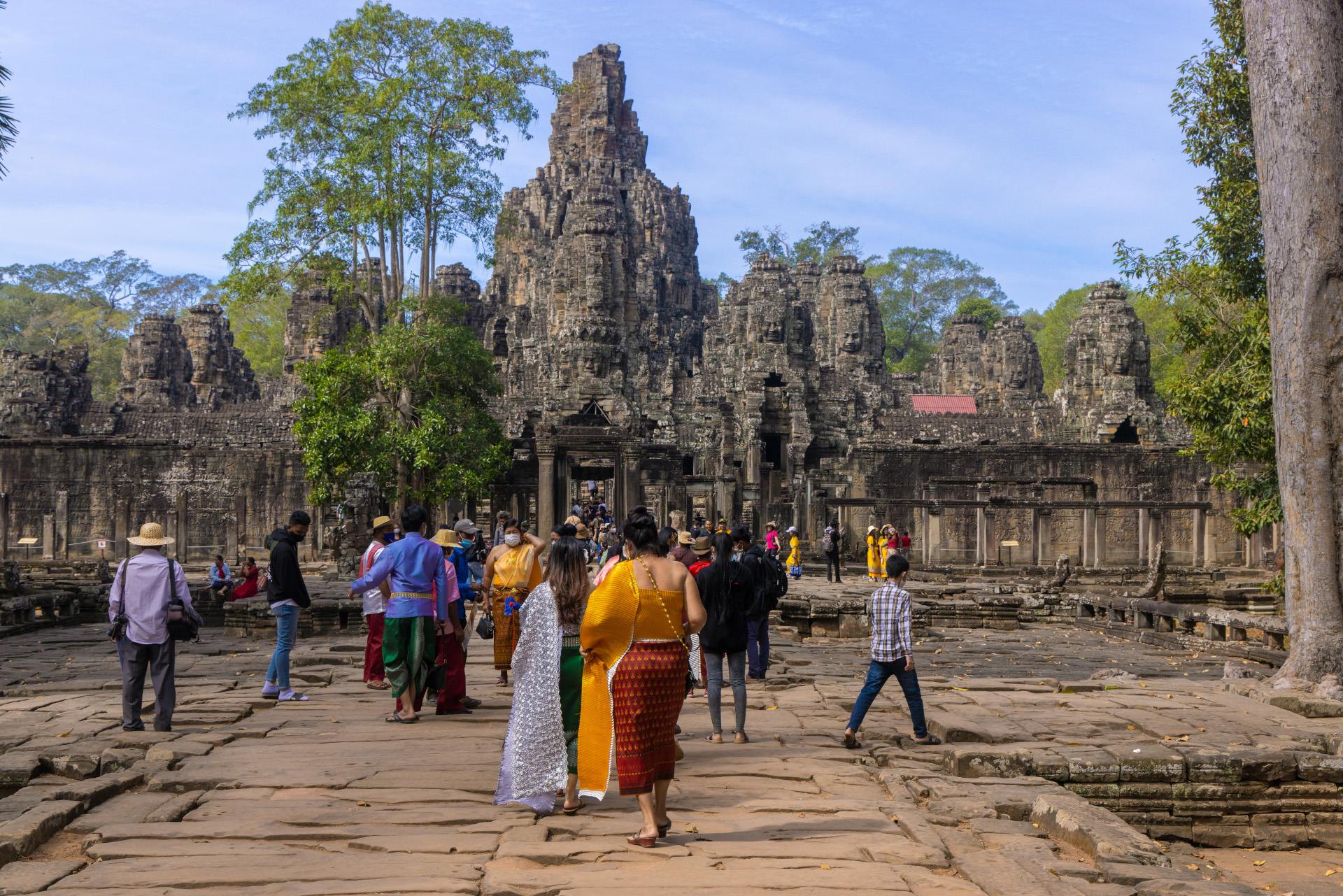 Visitors explore ancient stone ruins surrounded by lush greenery on a sunny day.