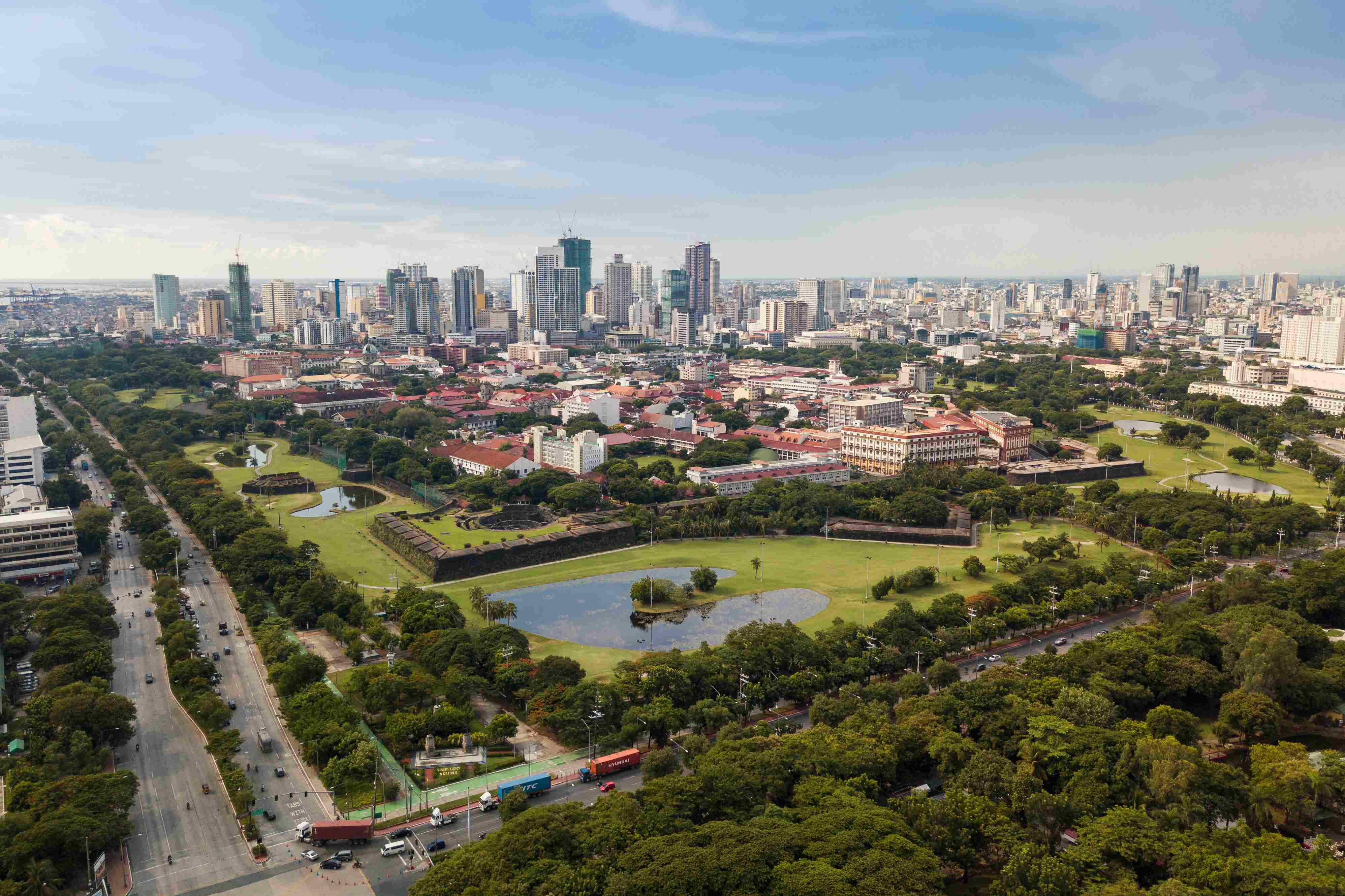 Aerial of Intramuros, an old historic walled city, surrounded by golf courses, and Manila skyline in background