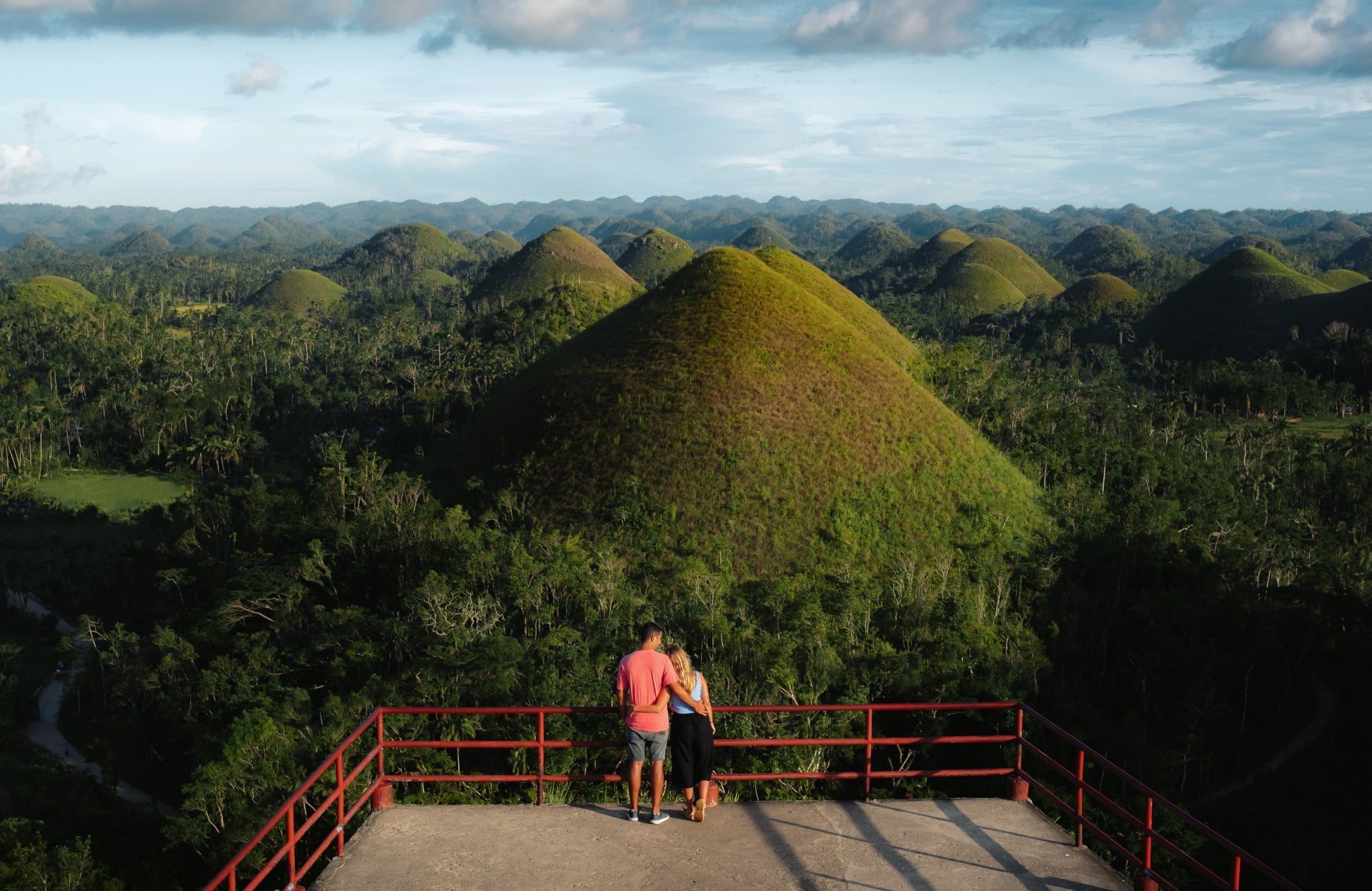 Travelers look out on panoramic views at sunset in the Chocolate Hills of Bohol, Philippines