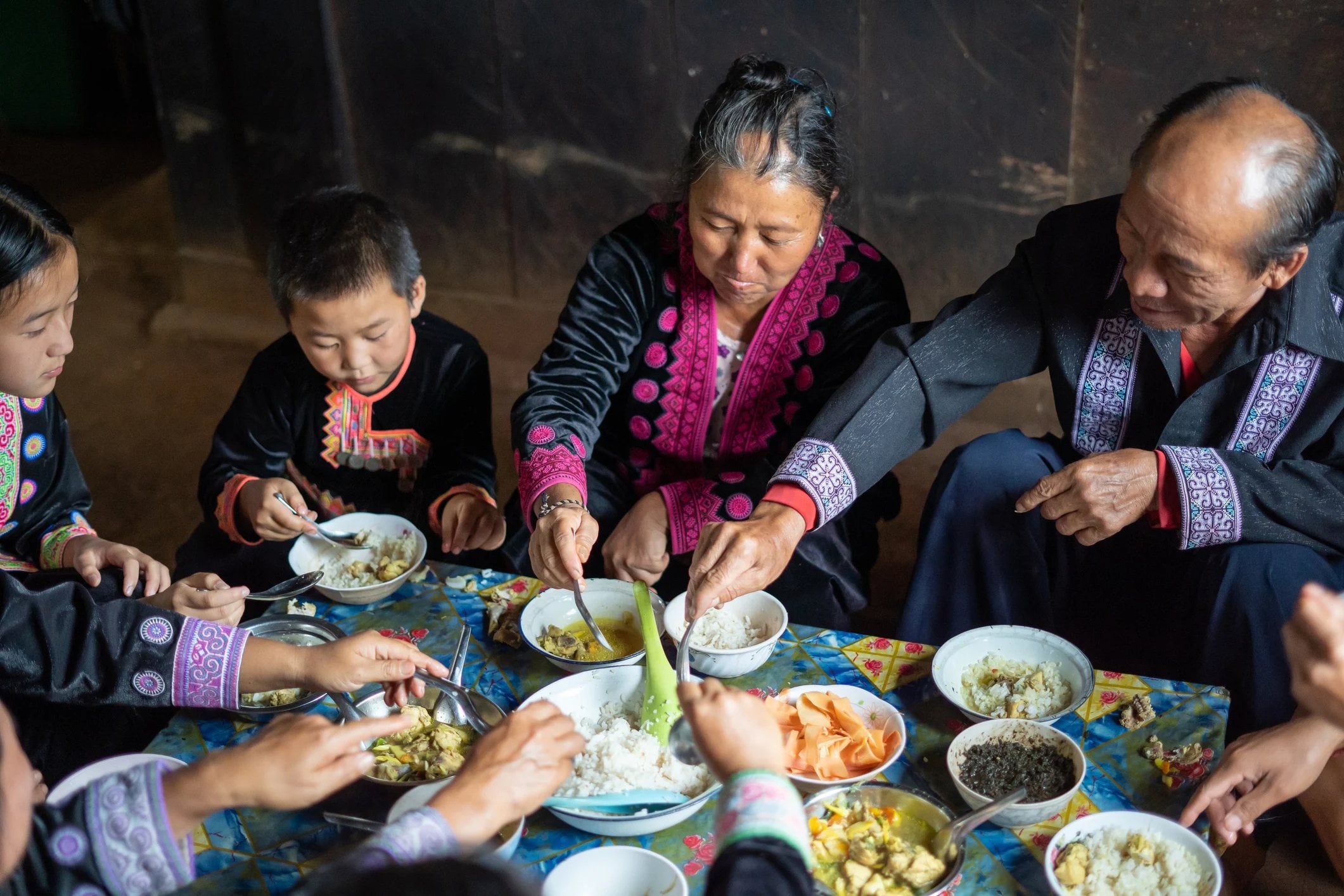 A family sits together sharing a meal, enjoying traditional dishes in a warm, cozy setting.