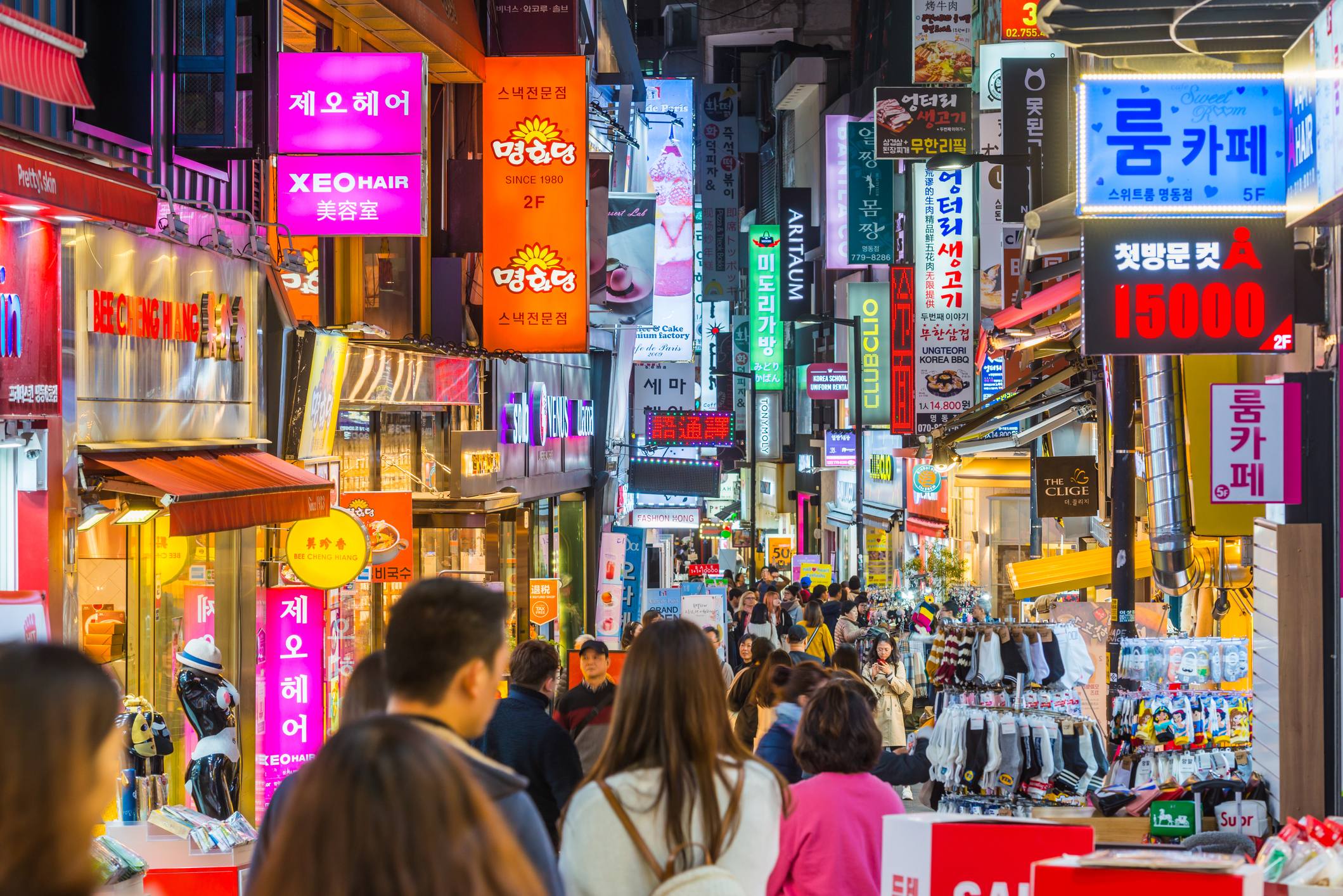 Busy street in South Korea filled with colorful signs, shops, and a crowd of people exploring.