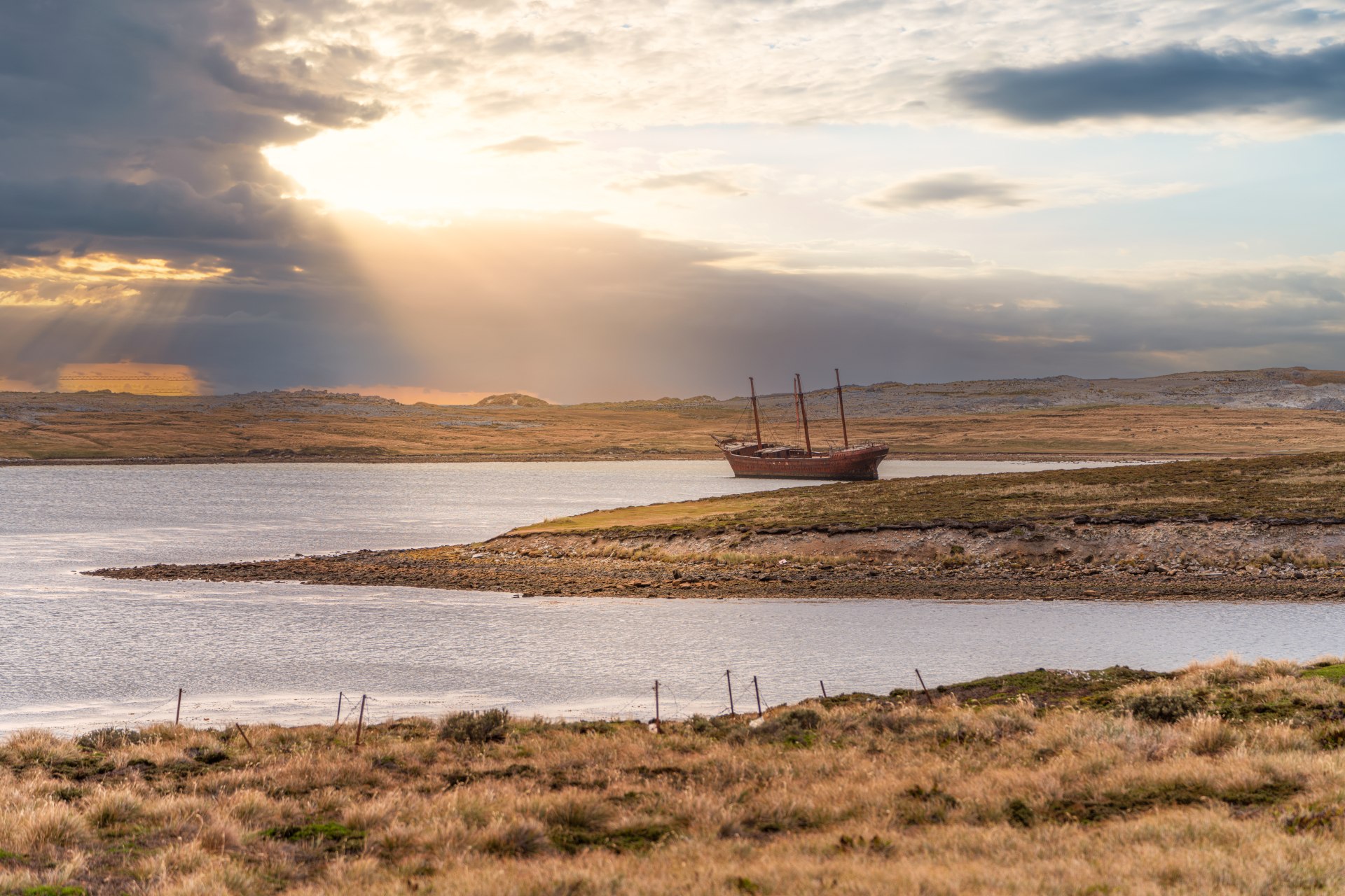 An old whaler wreck in Whalebone Cove off Stanley in the Falkland Islands, town of Stanley in the background
