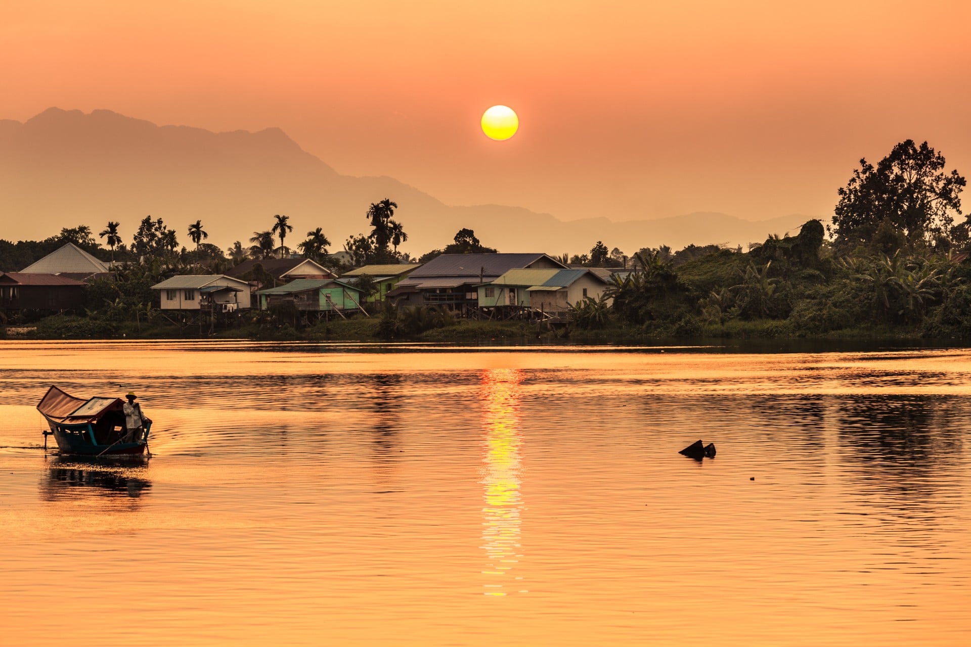 Kuching, Borneo Sunset along the river with a local village and mountains in the background
