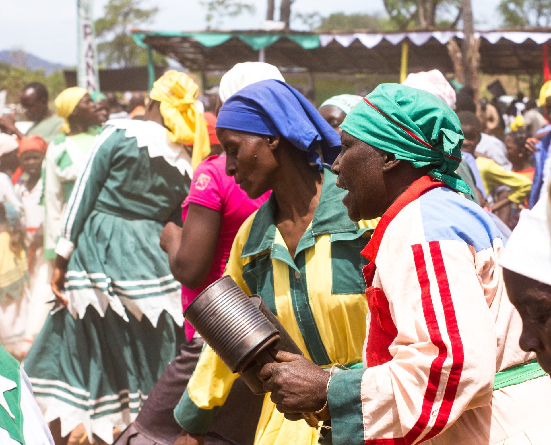 A vibrant scene of people dancing and celebrating, wearing colorful traditional attire at a lively outdoor event.