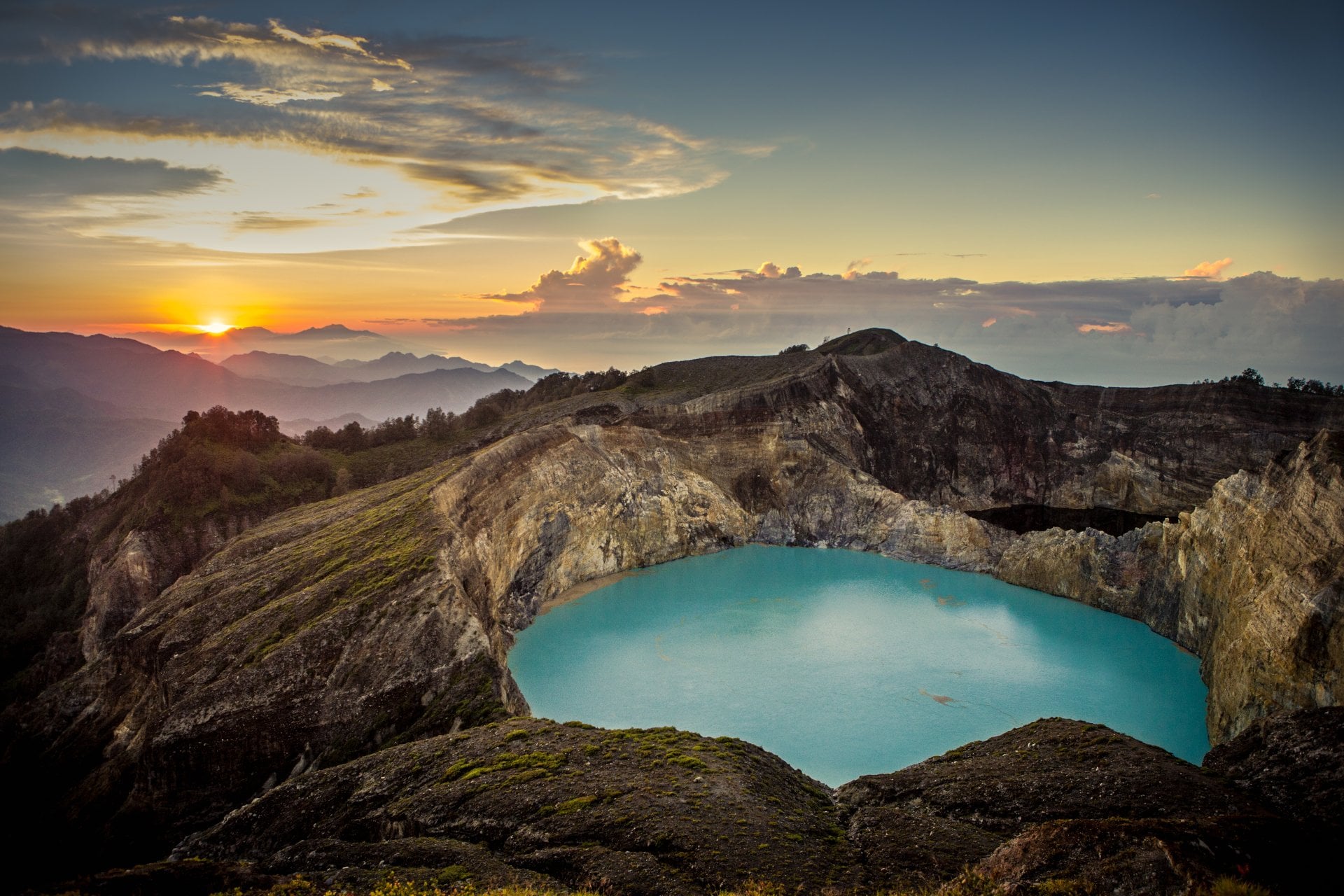 Sunrise on top of the Kelimutu volcano, featuring beautiful aqua colored crater lake at centre. Flores, Indonesia.