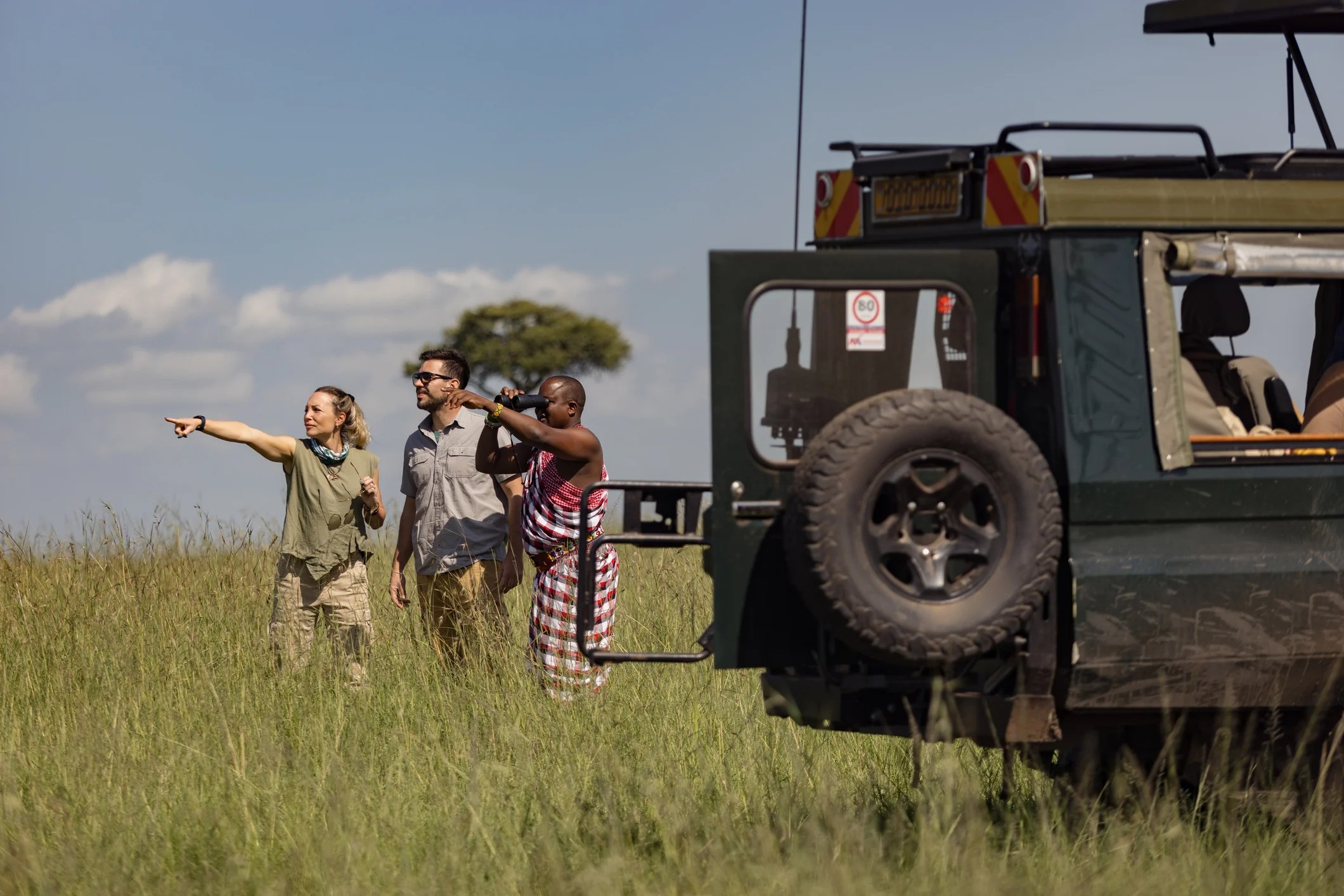 Two travellers with a Maasai tracker guide on safari in Kenya.