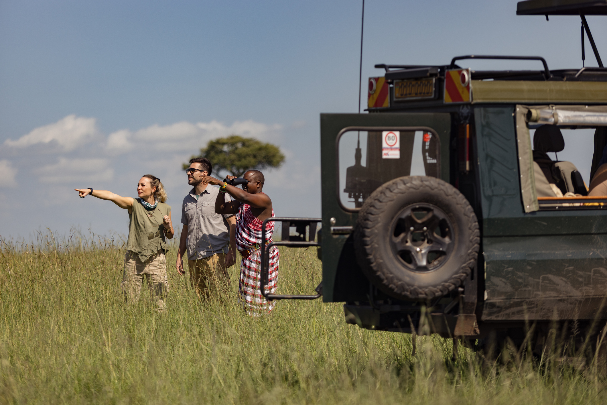 Two travellers with a Maasai tracker guide on safari in Kenya.