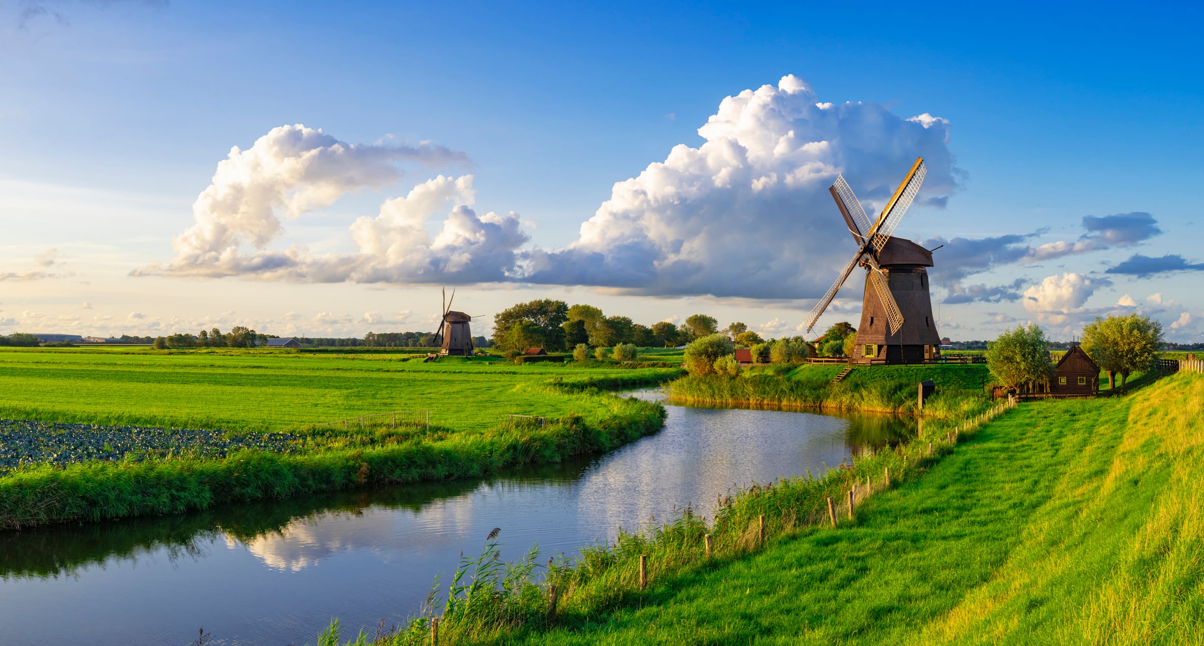 A view of a windmill alongside a canal and farm fields