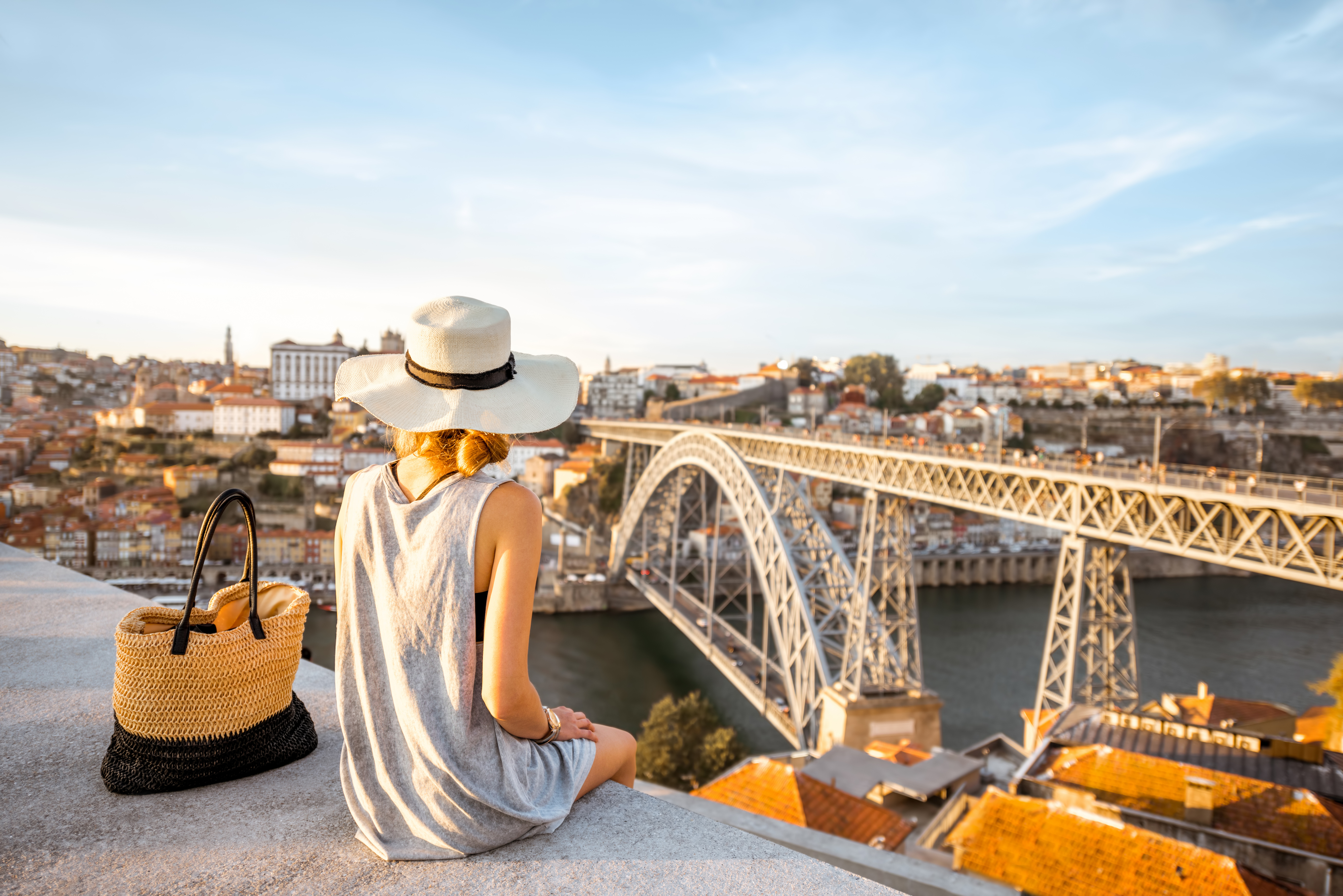 Porto, Portugal a woman sitting on a ledge looking over river and bridge in Porto