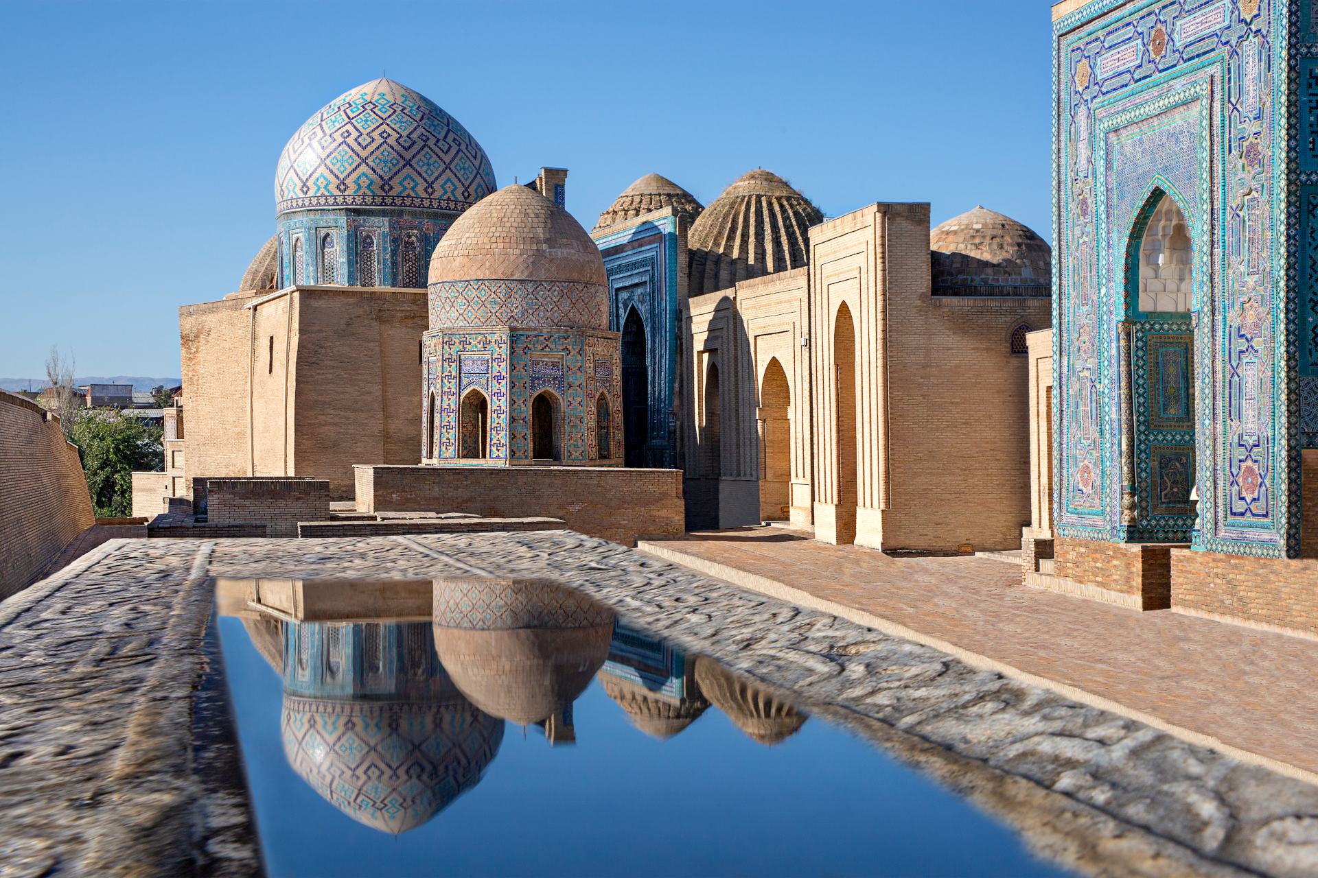 Samarkand, Uzbekistan Mausoleums and domes of the historical cemetery of Shahi Zinda and their reflections in puddle, Samarkand, Uzbekistan.