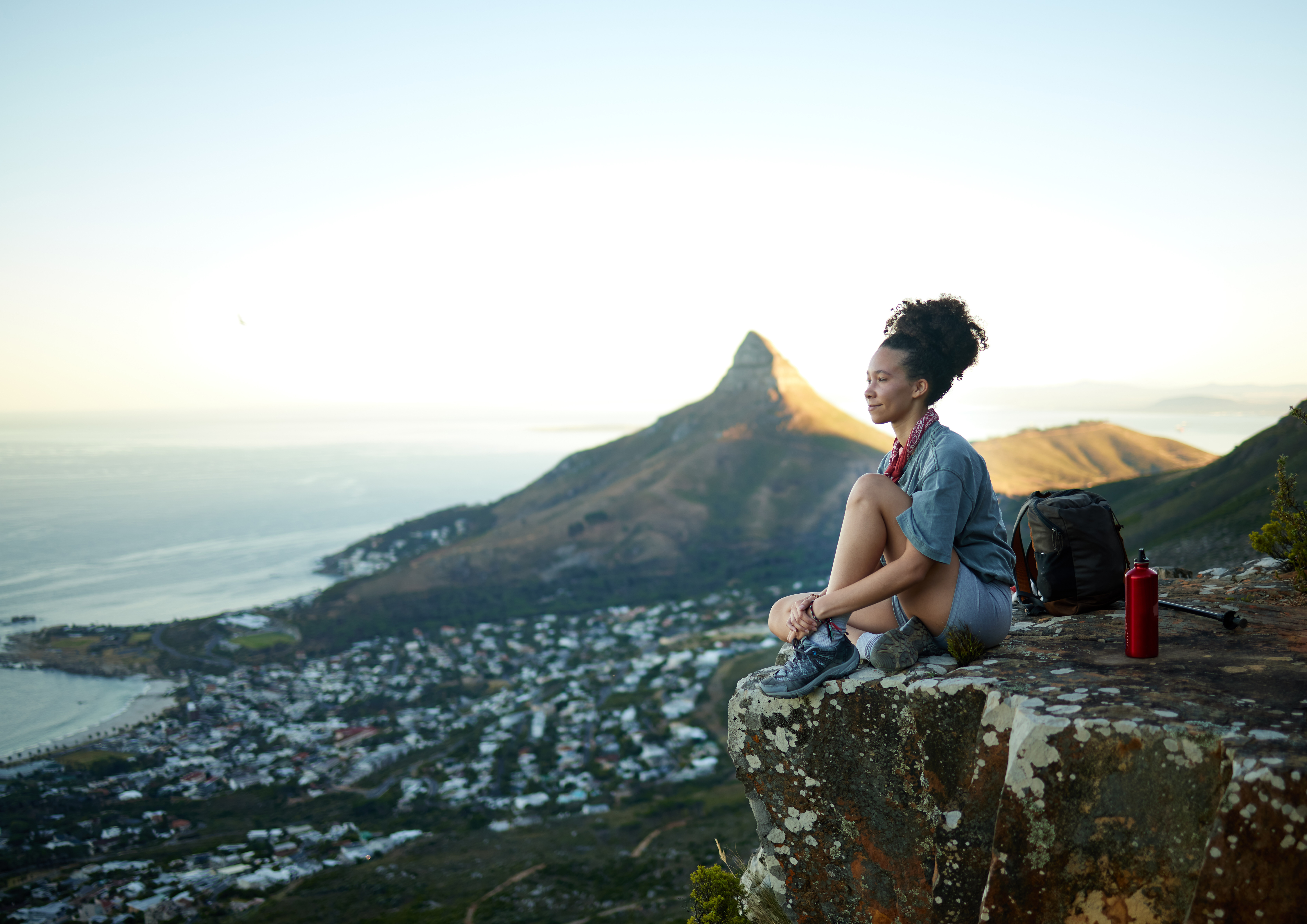 woman on the edge of a mountain overlooking city and ocean