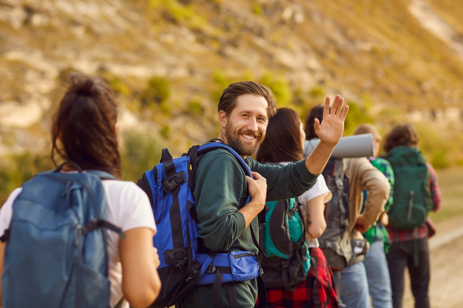 smiling man with a beard packing with others and looking at camera