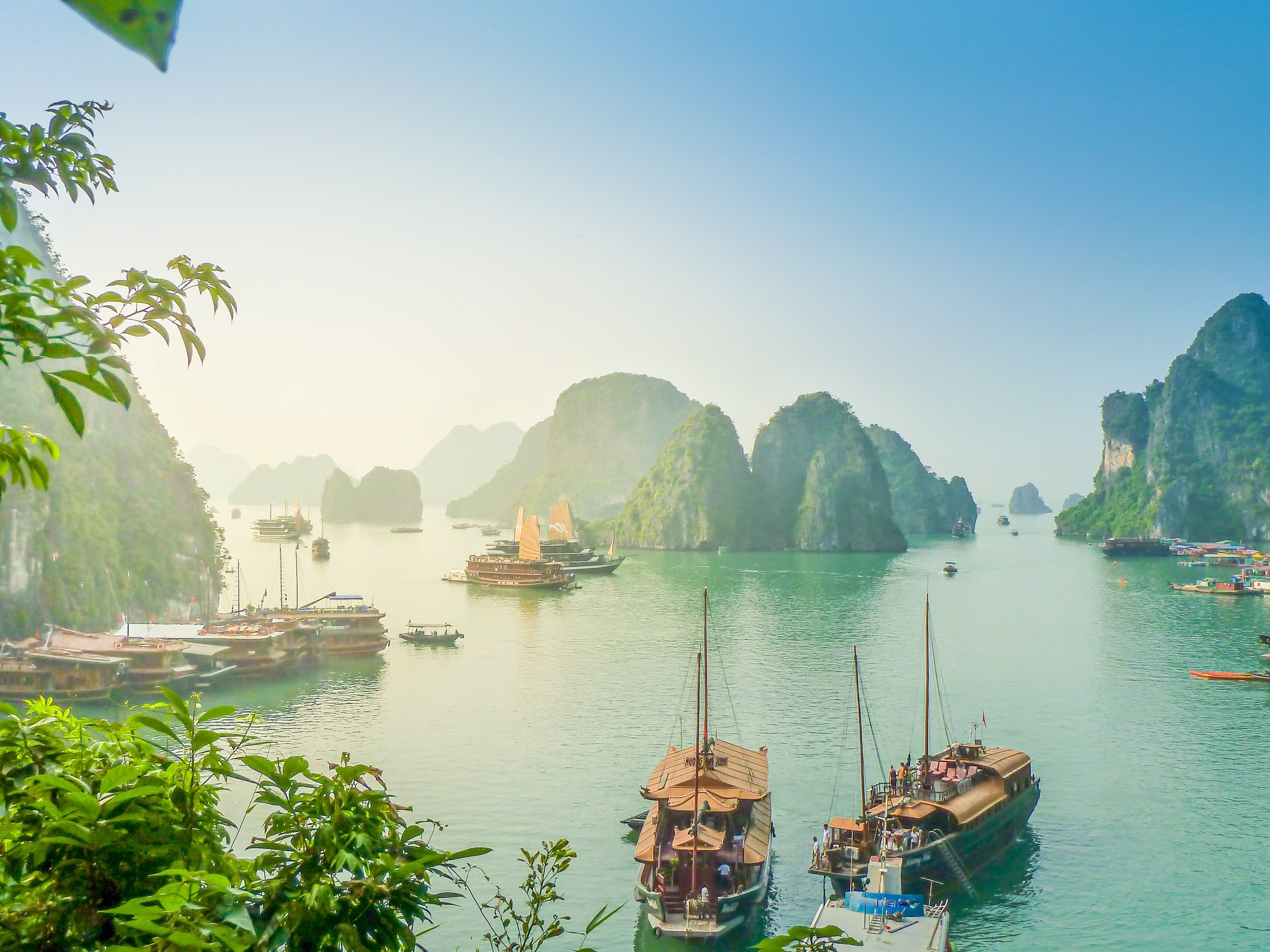 View of Halong Bay with junker boats on the water with a backdrop of karst mountains.
