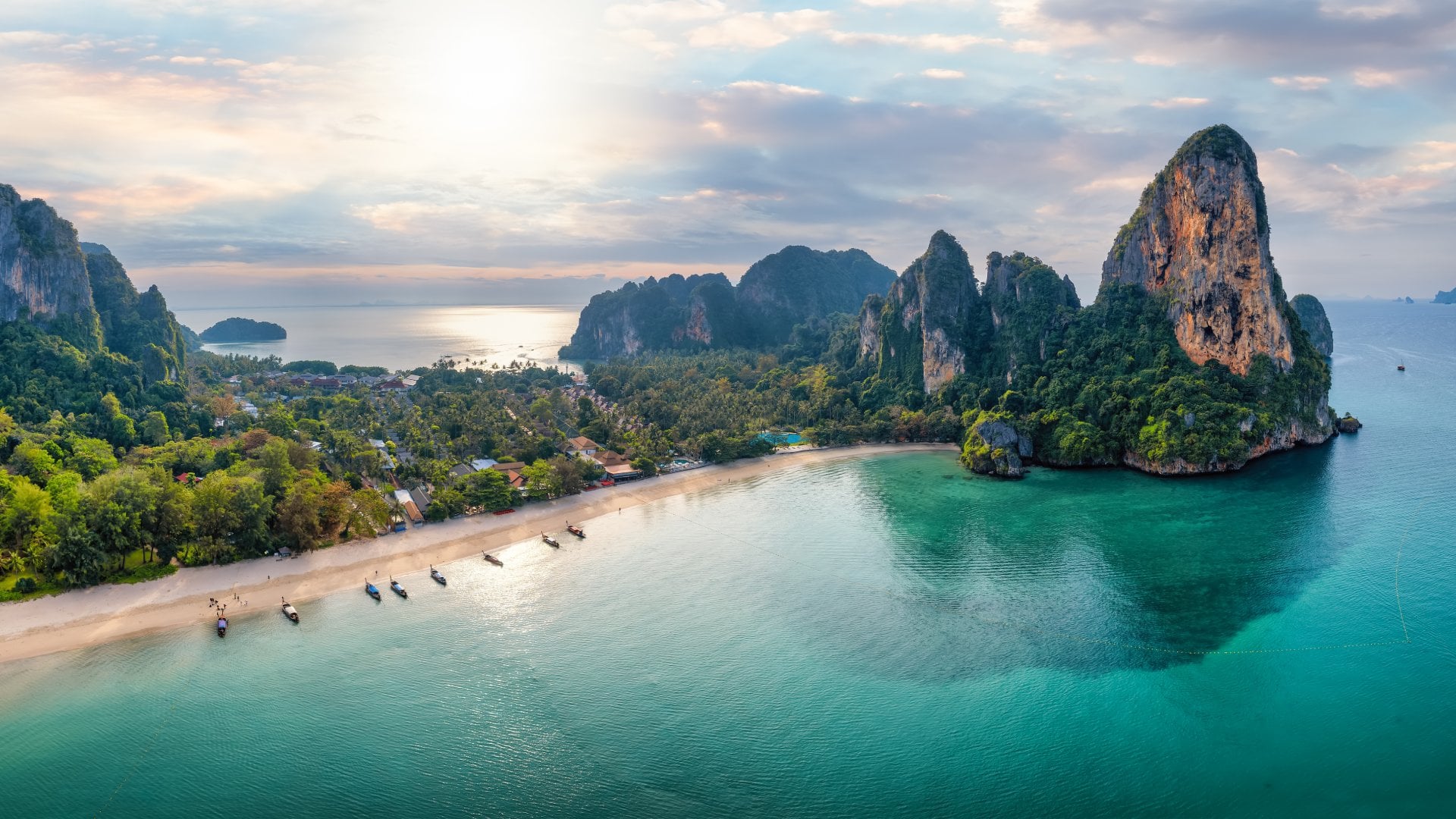 Panoramic aerial view of the beautiful Railay beach, lush rain forest and emerald sea during morning sunrise without people